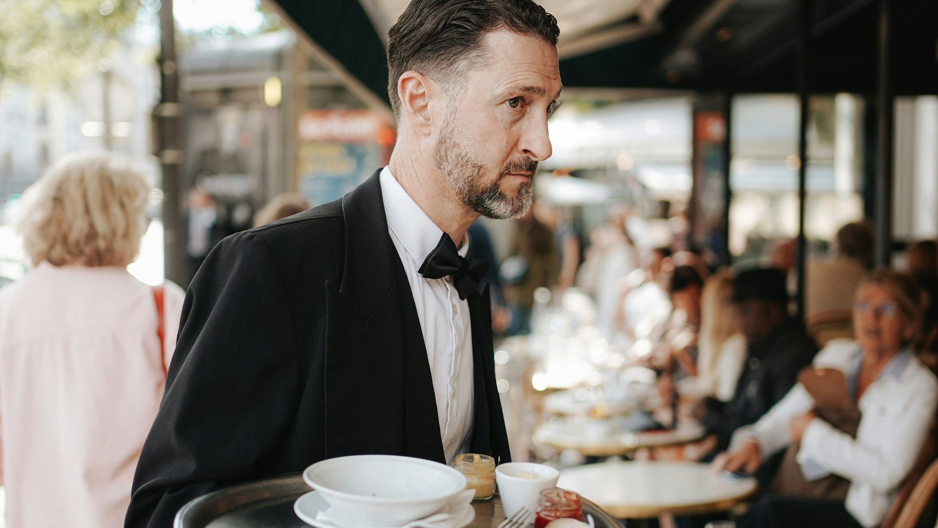 A man in a tuxedo carrying a tray of food