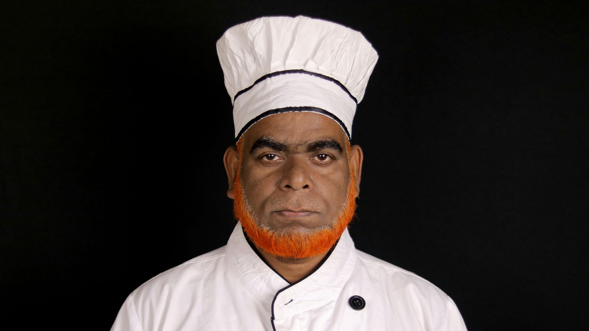 A chef in a white uniform with a tall hat.