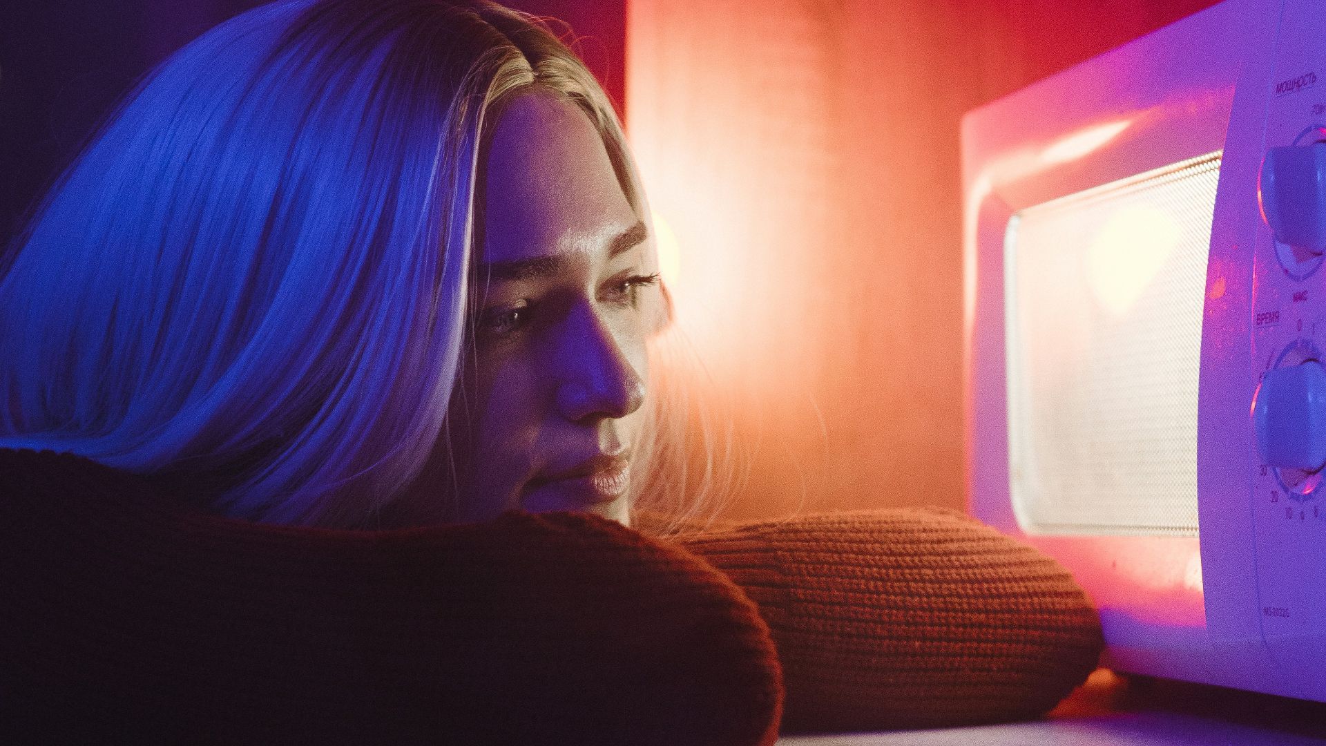 woman in black long sleeve shirt sitting beside white microwave oven