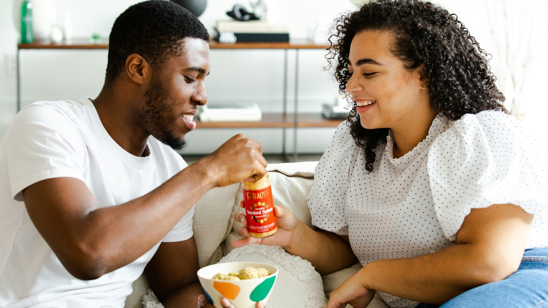 man in white crew neck t-shirt and blue denim jeans sitting on white sofa chair