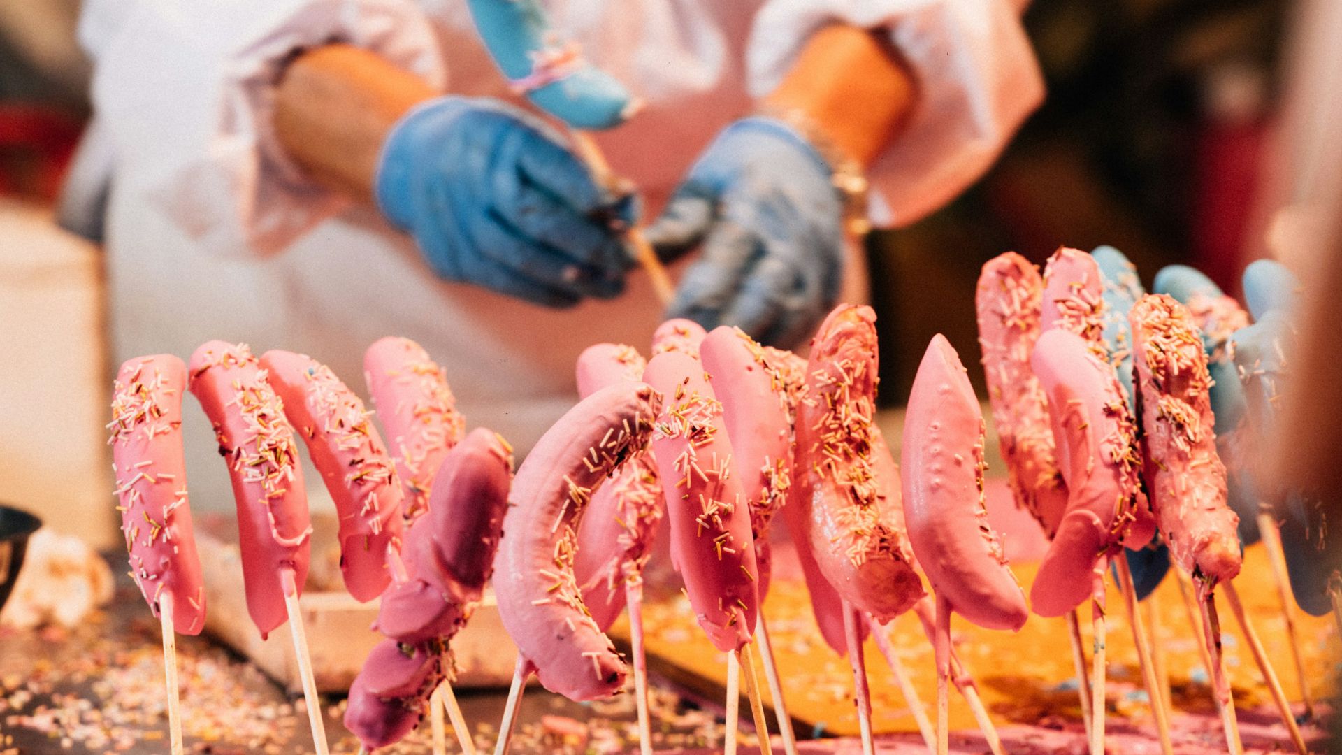 Person making pink candy floss on sticks