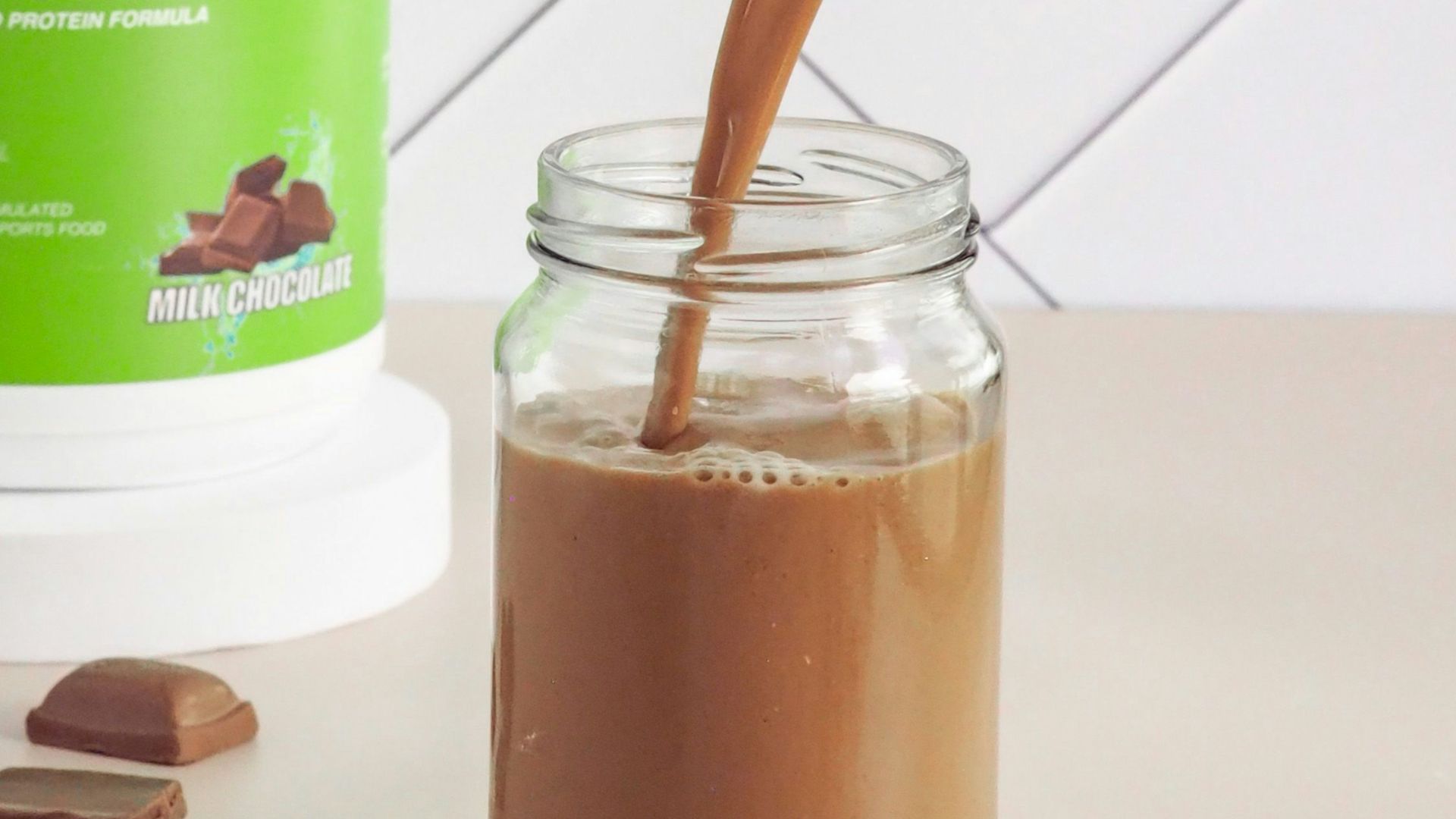 a person pouring a drink into a mason jar