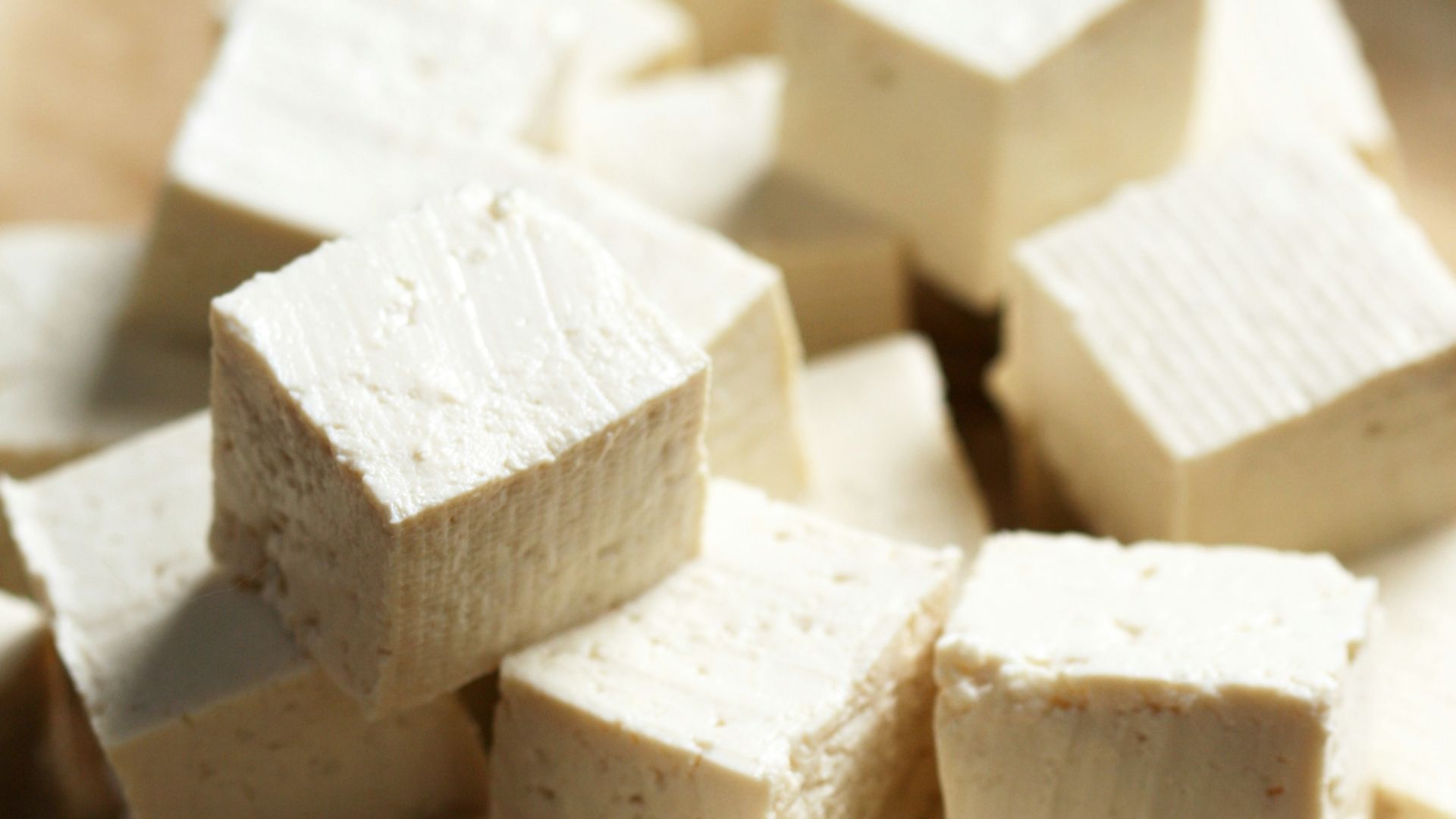 A pile of tofu cubes sitting on top of a cutting board