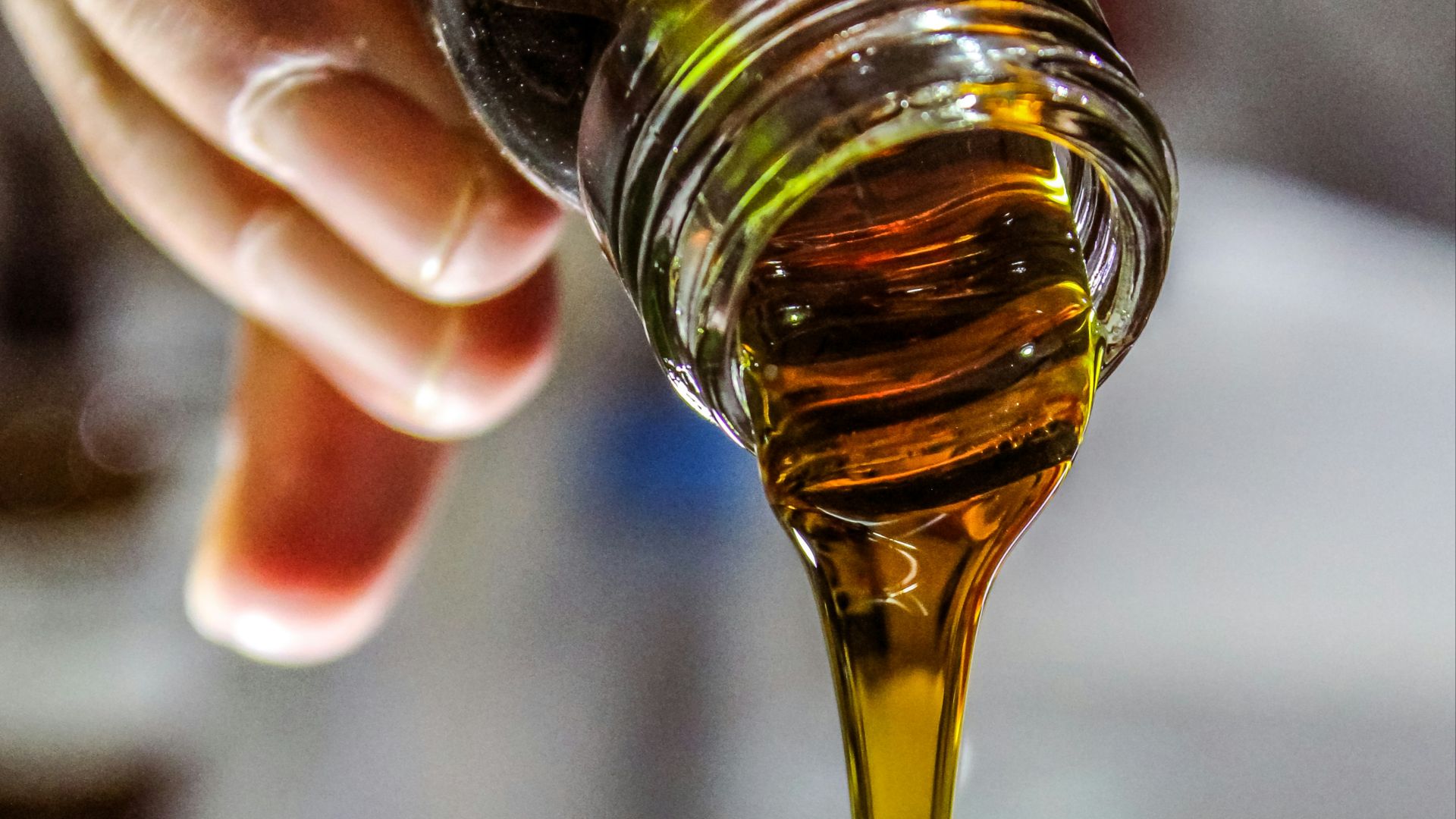 person holding clear drinking glass with brown liquid