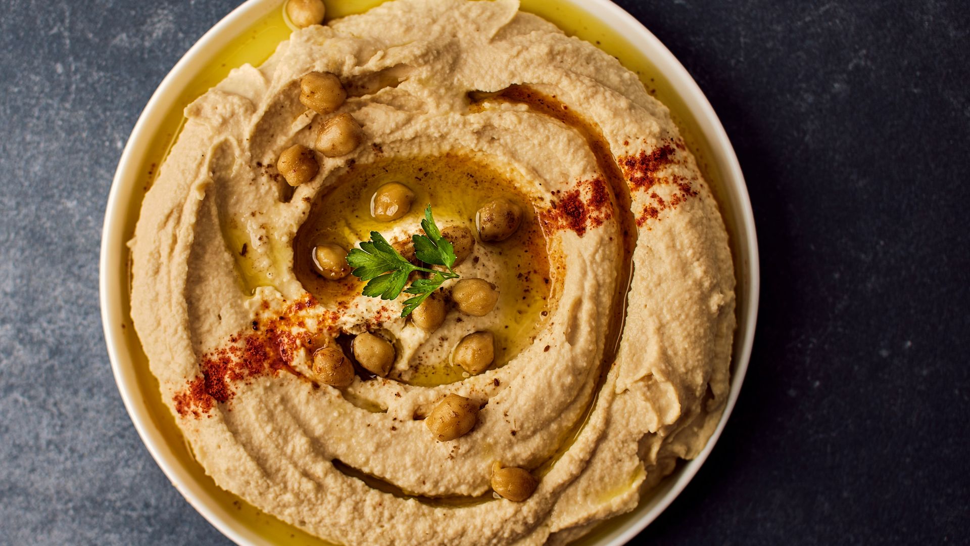 a bowl of hummus with a garnish on top