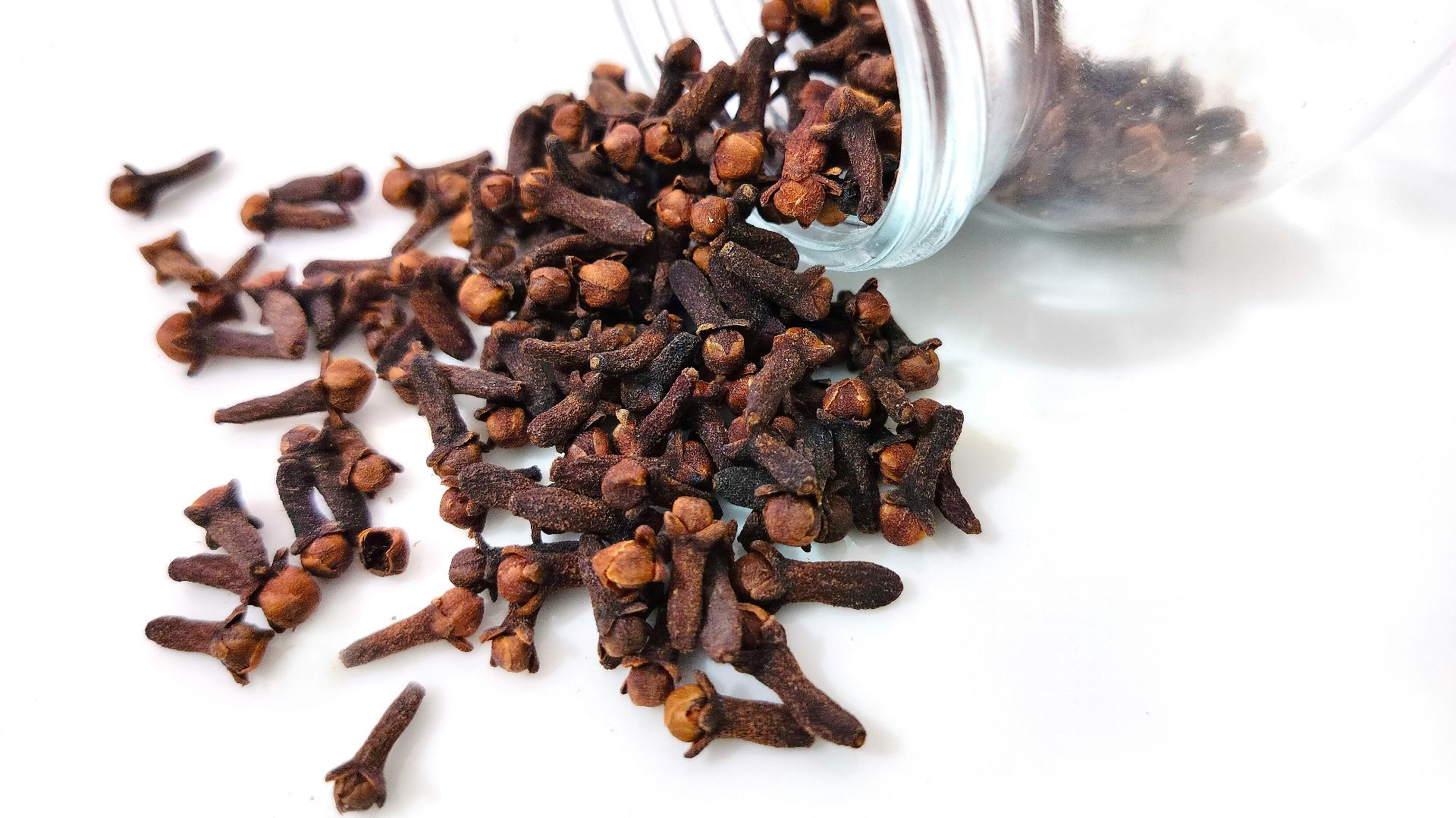 a glass jar filled with cloves on top of a white table