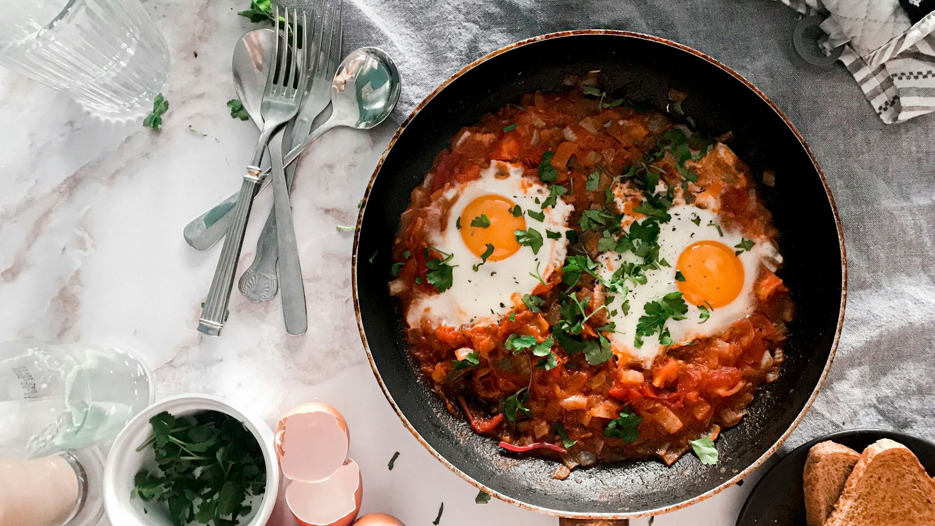 tomato soup on black cooking pan beside stainless steel fork and bread knife