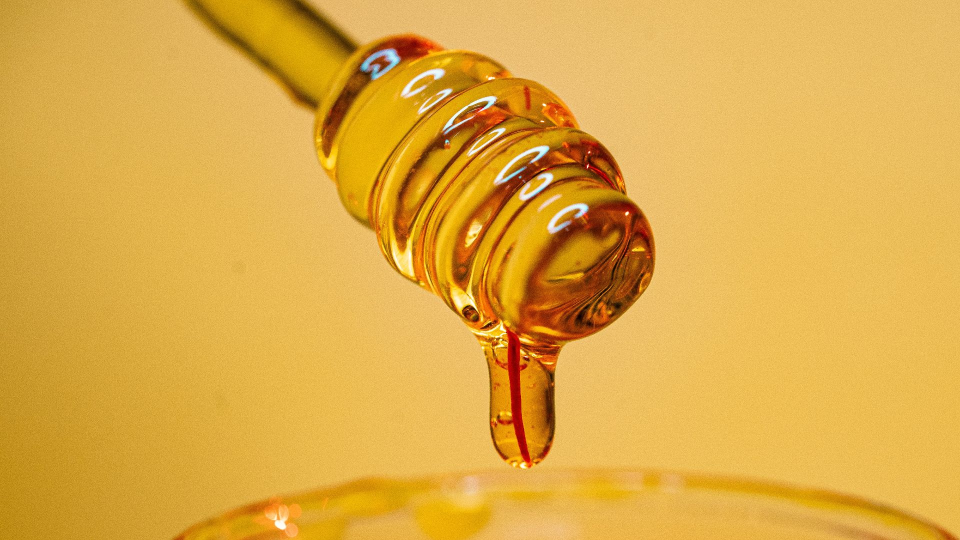 clear glass bottle pouring red liquid on clear drinking glass