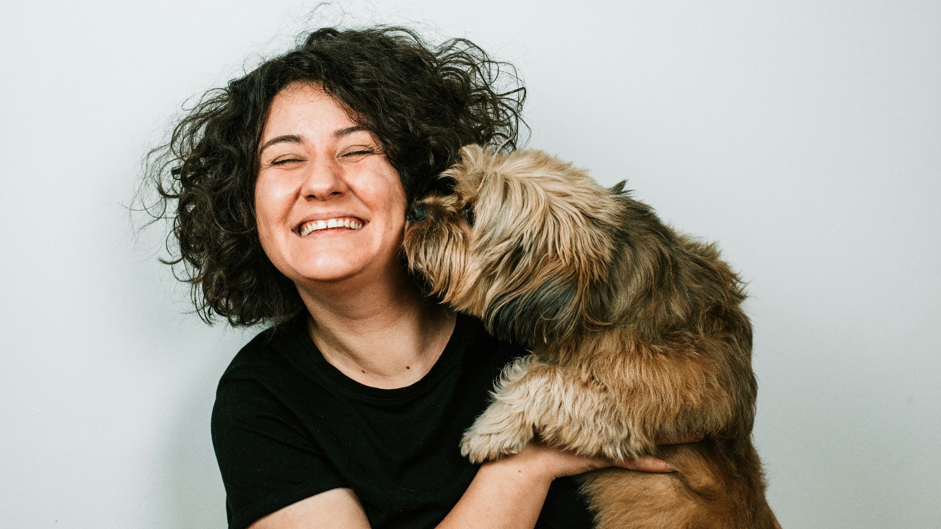 dog kissing woman in black crew-neck shirt