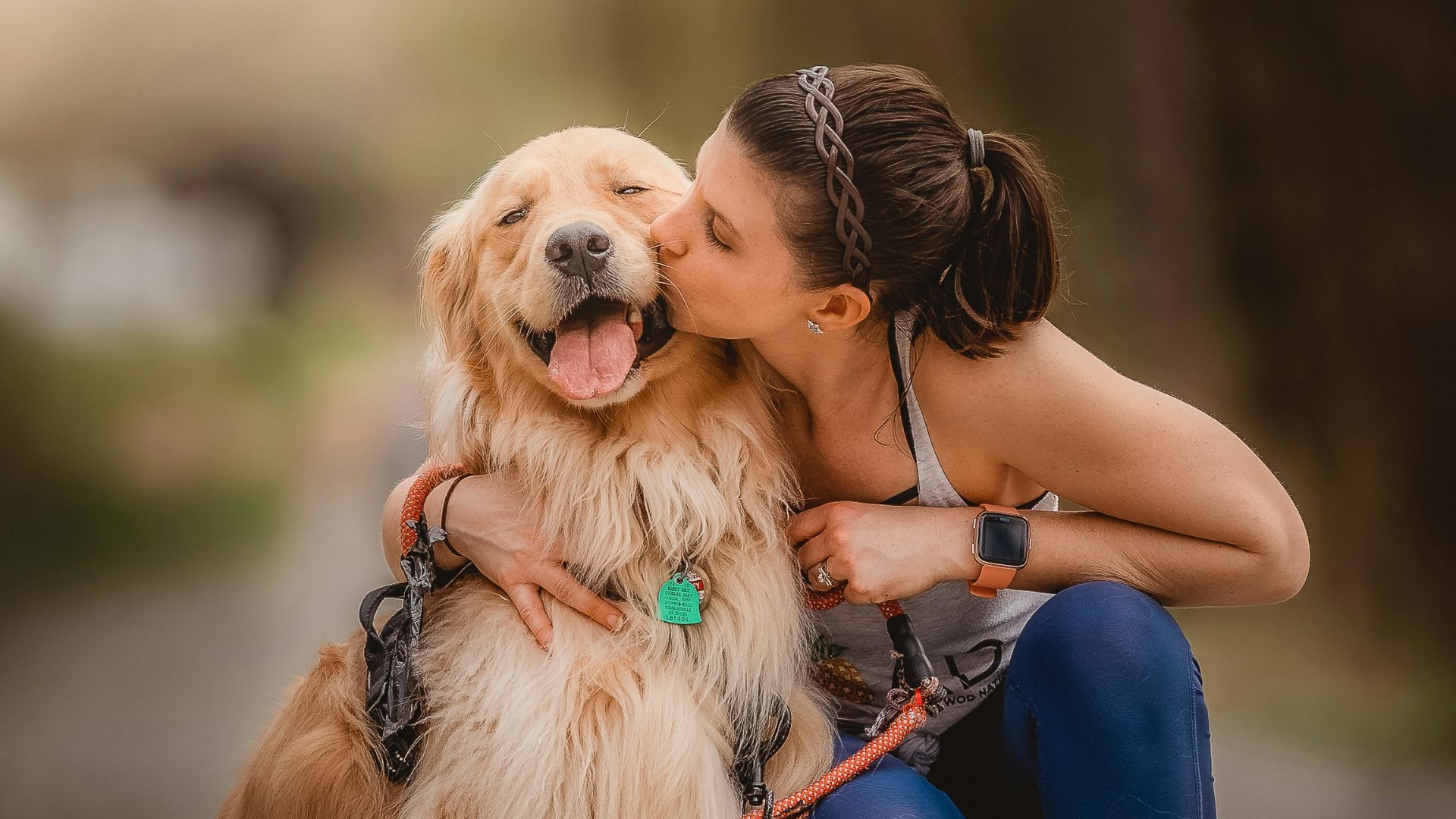 a woman kissing her dog on the cheek