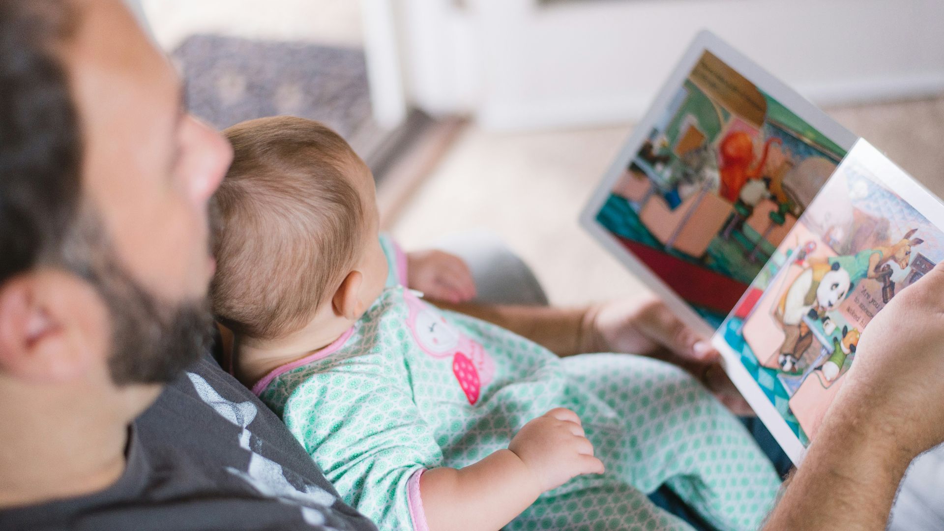 person carrying baby while reading book