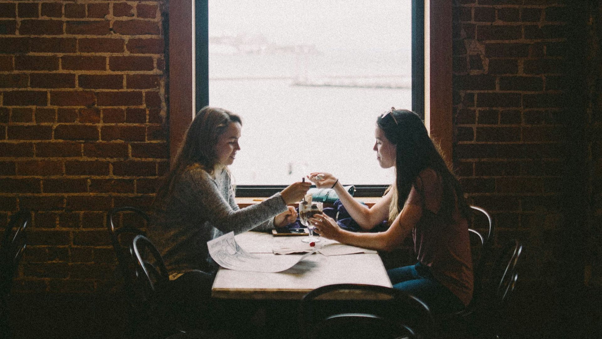 woman sitting in front of woman near window