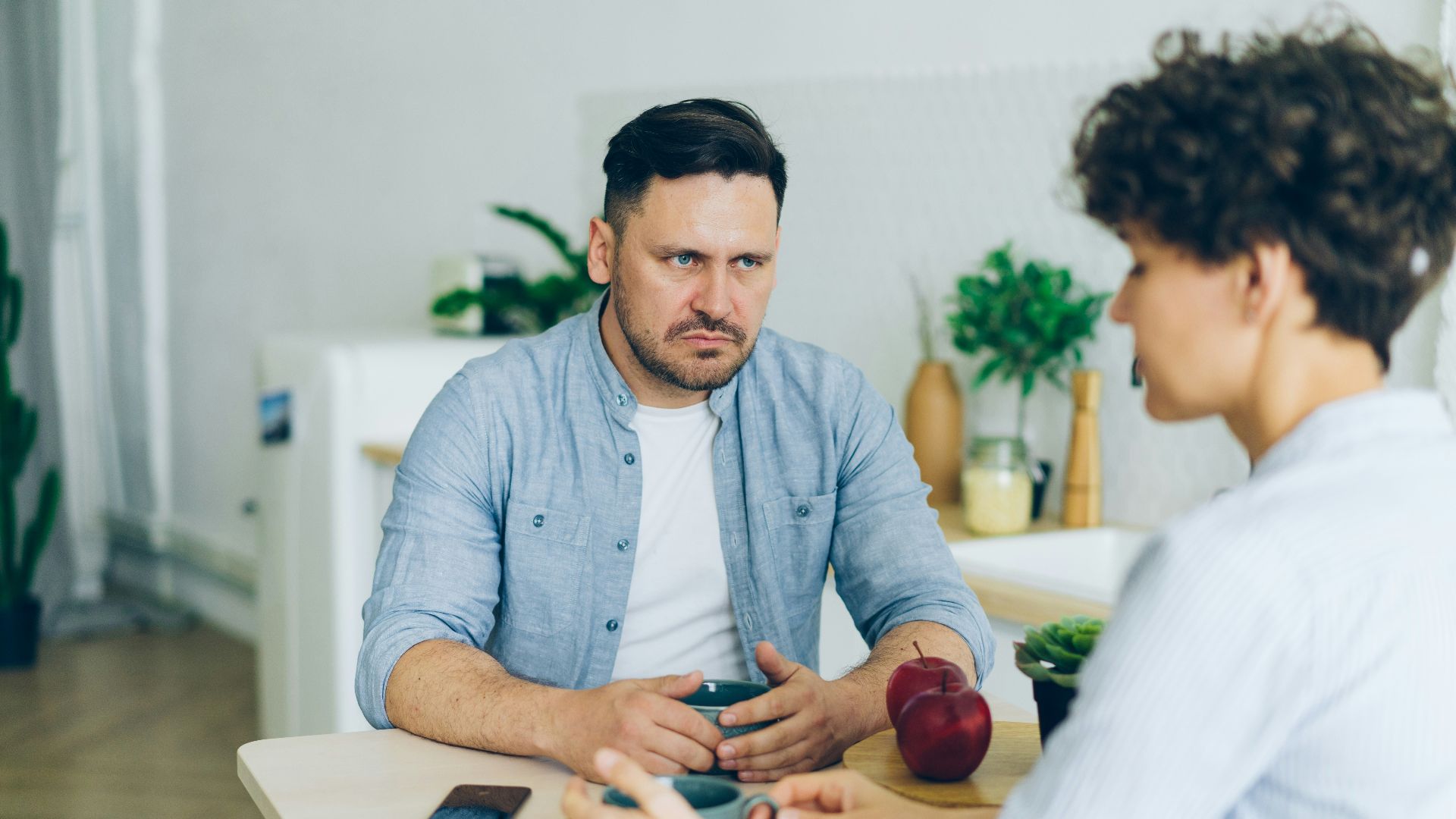 a man sitting at a table talking to a woman