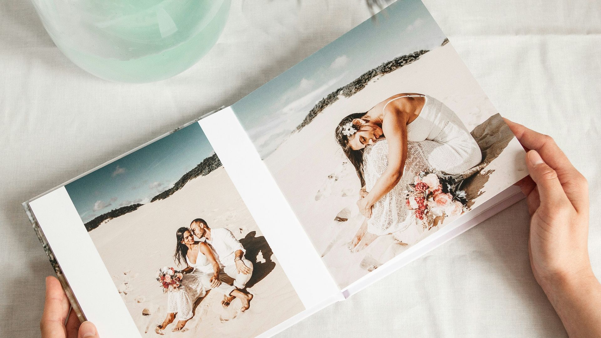 a person holding a photo book open to a picture of a bride and groom