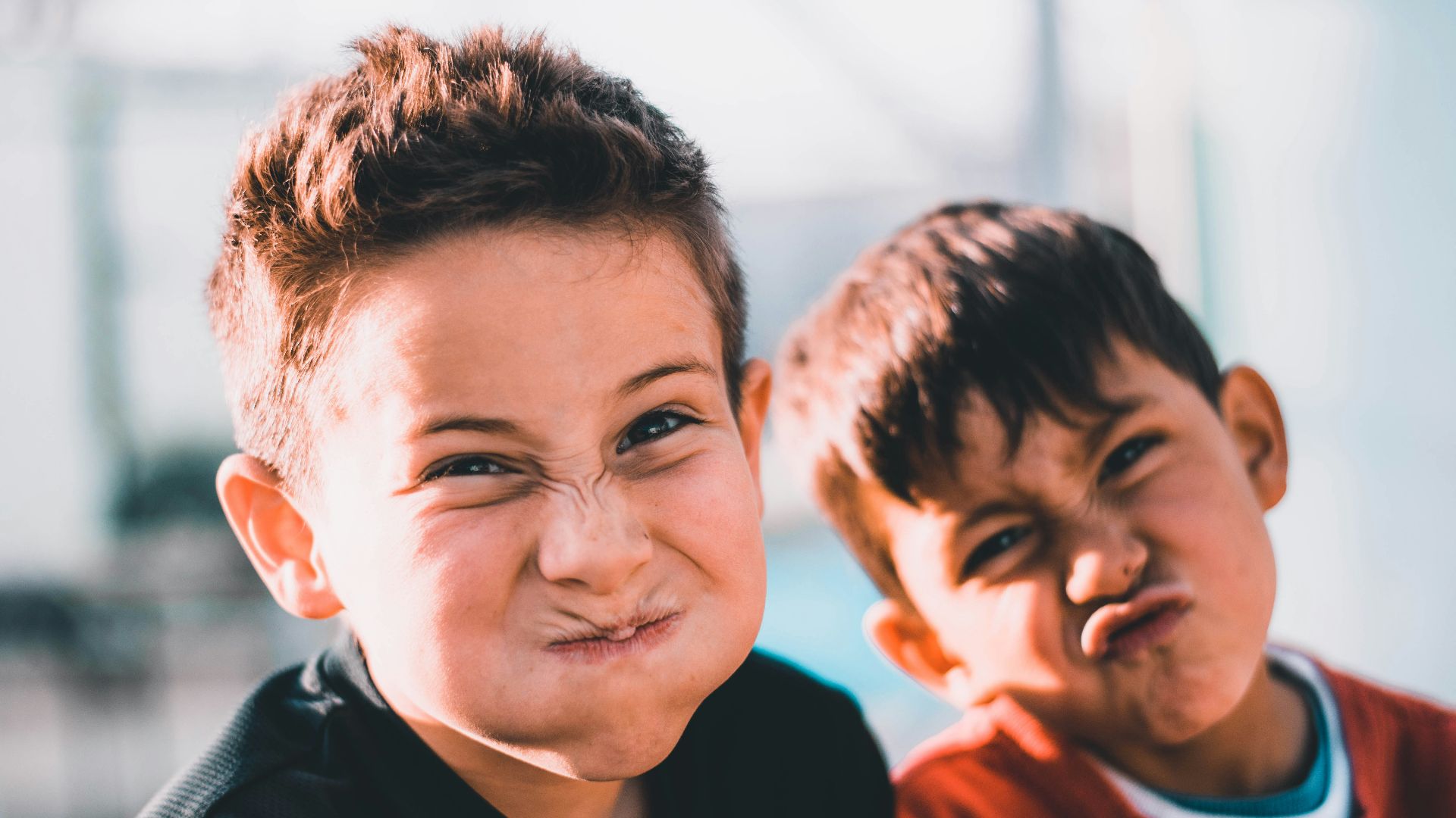 shallow focus photography of two boys doing wacky faces
