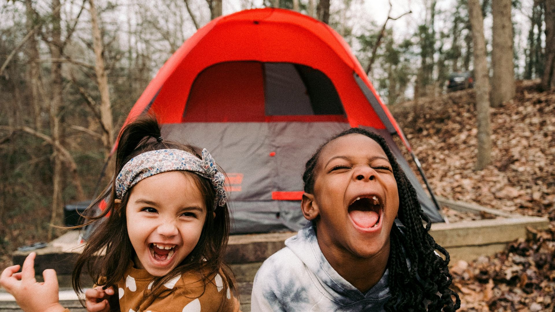a couple of young girls standing next to a tent