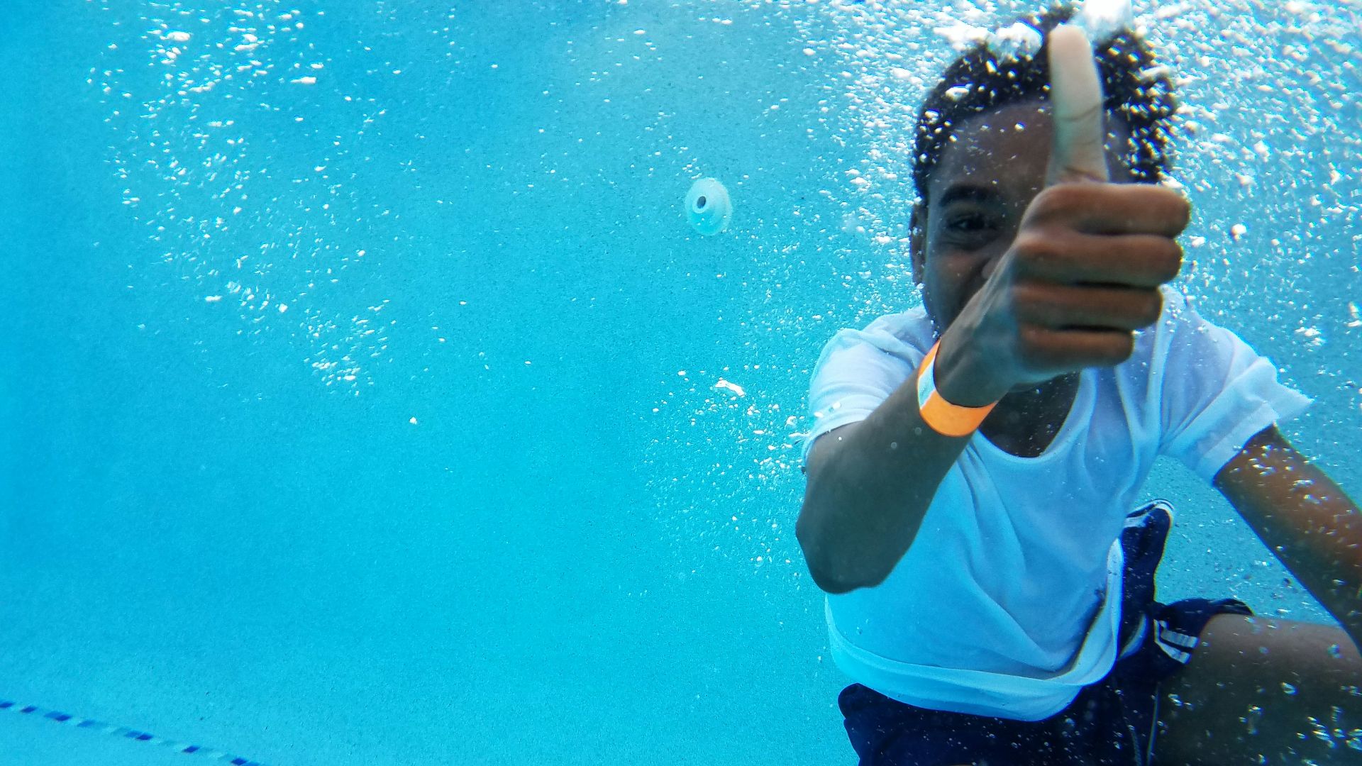 under water photography of boy showing thumb