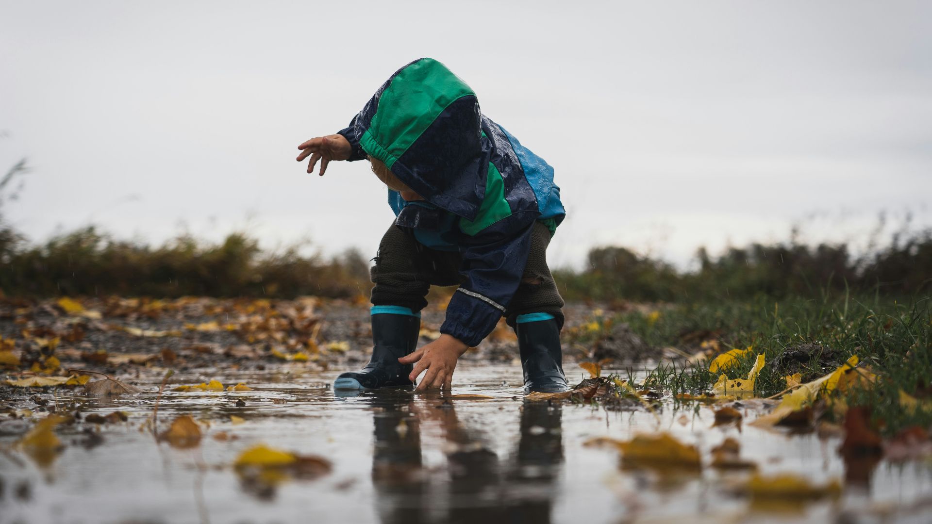 person in green jacket and black pants standing on water during daytime