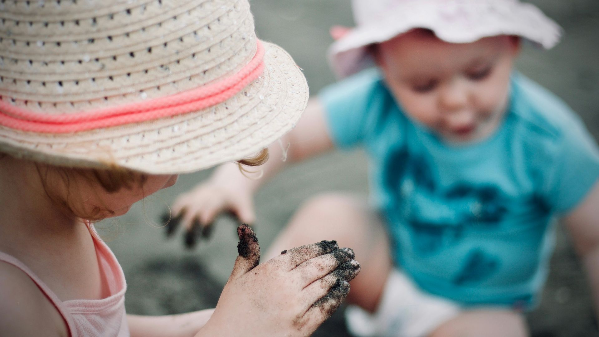 closeup photo of girl wearing sun hat holding sand
