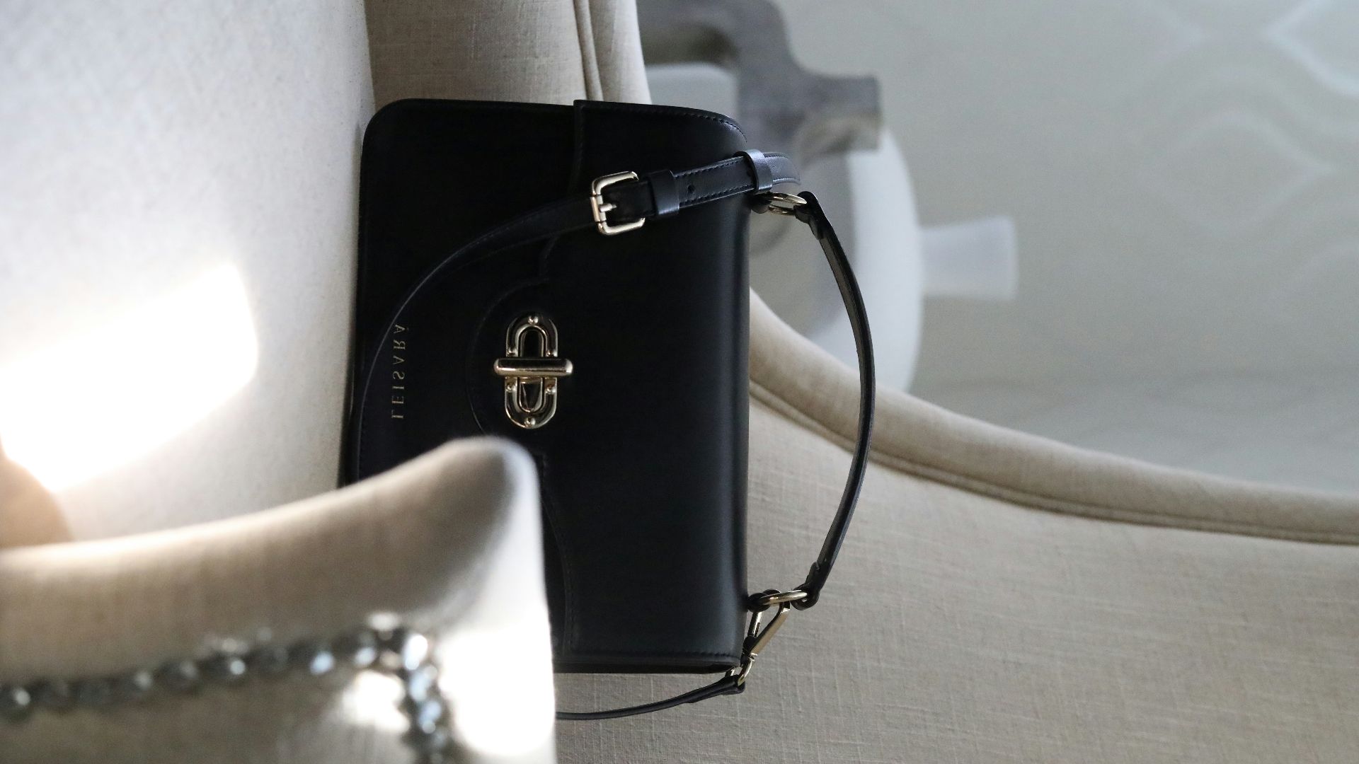 a black purse sitting on top of a white chair