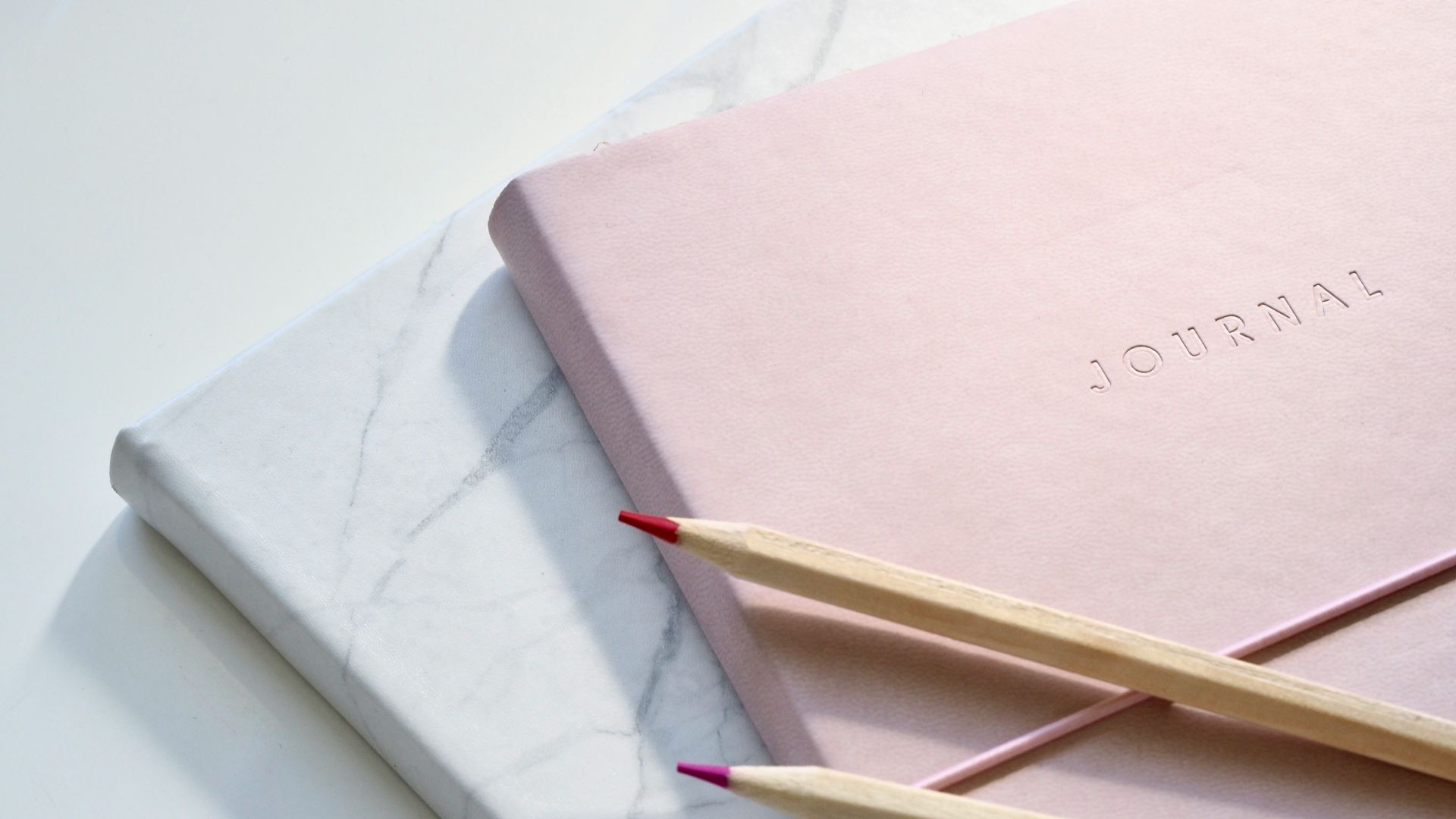 red and purple coloring pencils on pink journal