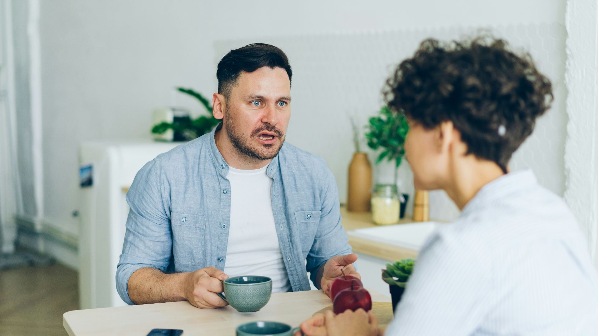 a man sitting at a table talking to a woman