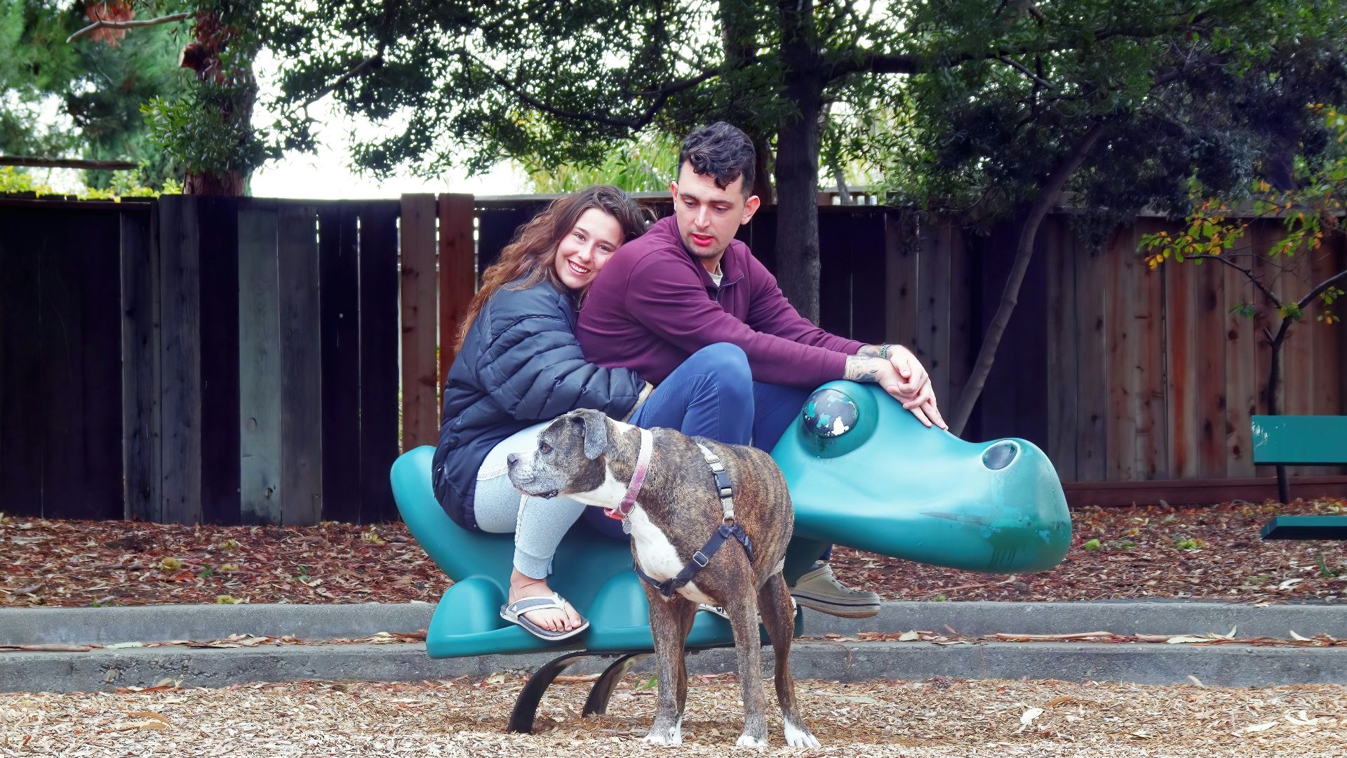a man and woman sitting on a bench with a dog