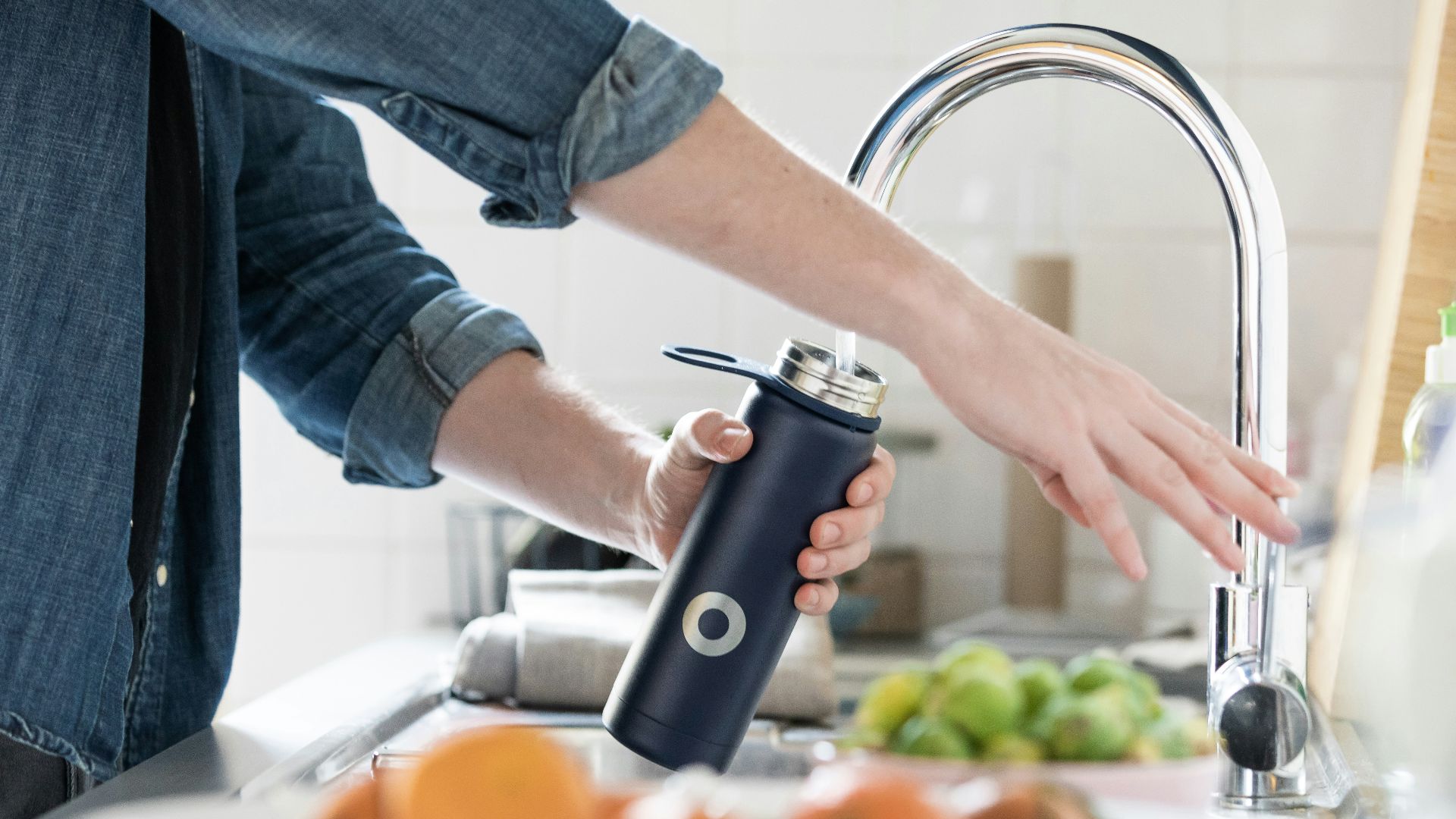 person in blue denim jacket holding stainless steel bottle