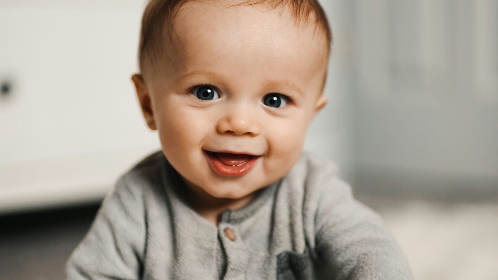 baby in gray sweater lying on white textile