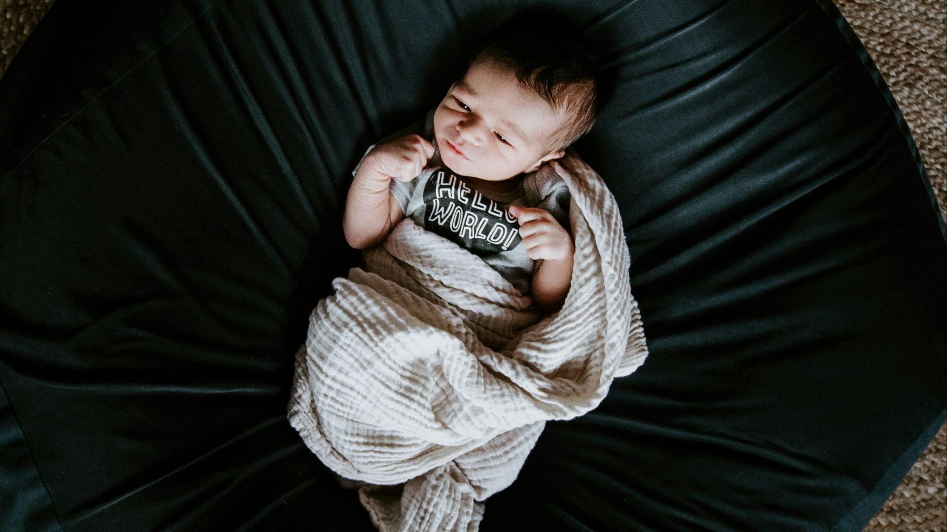 girl in white sweater and black pants lying on black round bed
