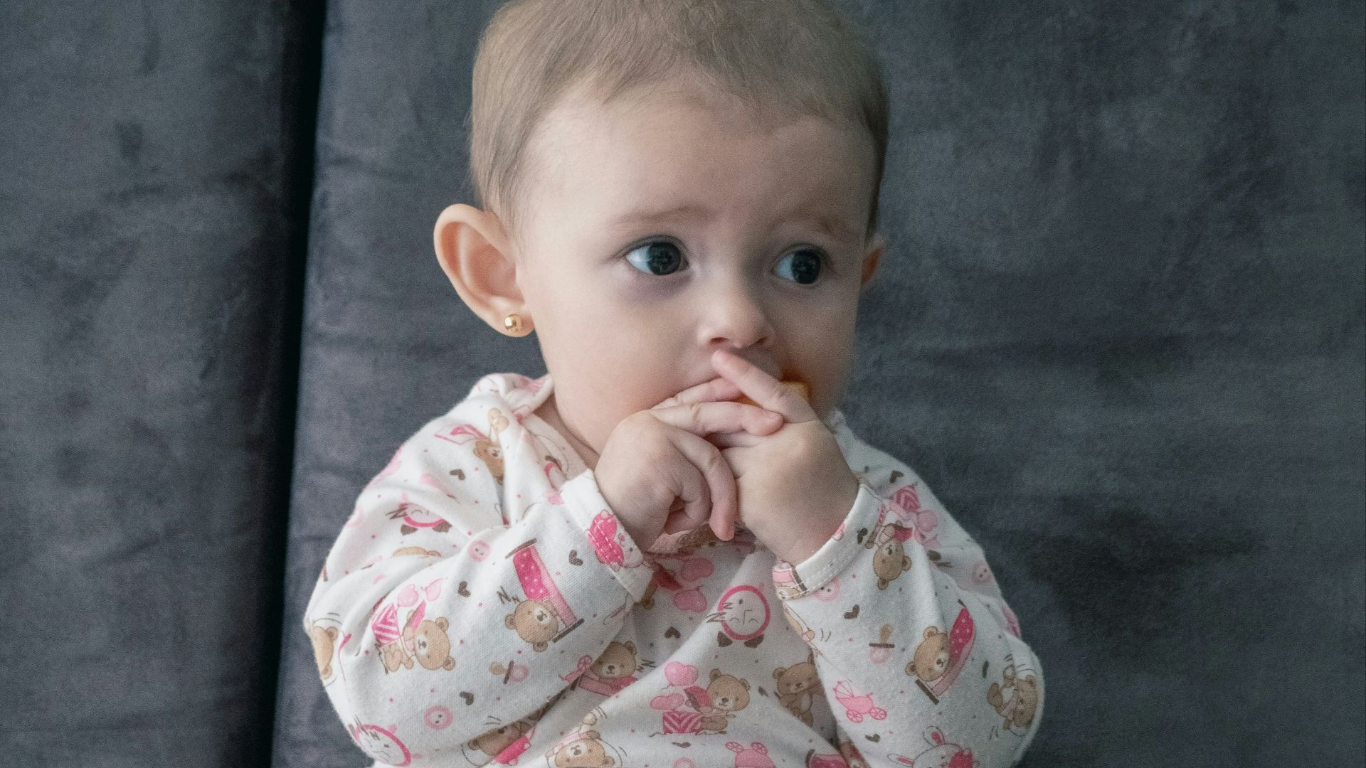 baby in white and pink onesie sitting on green and white ceramic plate