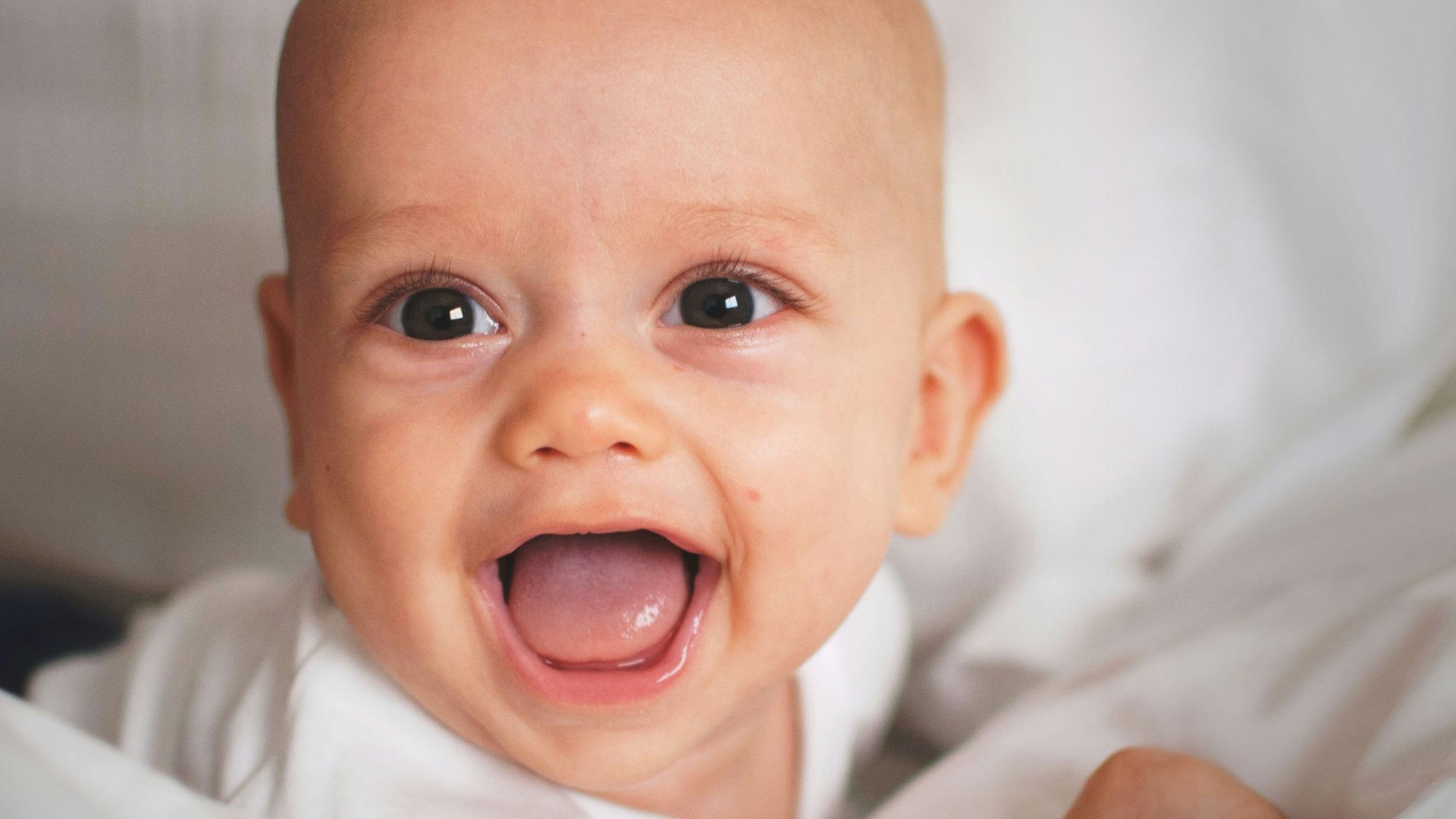 baby smiling on white cushion