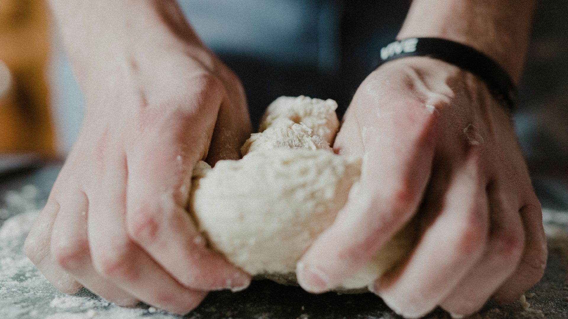 person holding white dough on brown wooden table