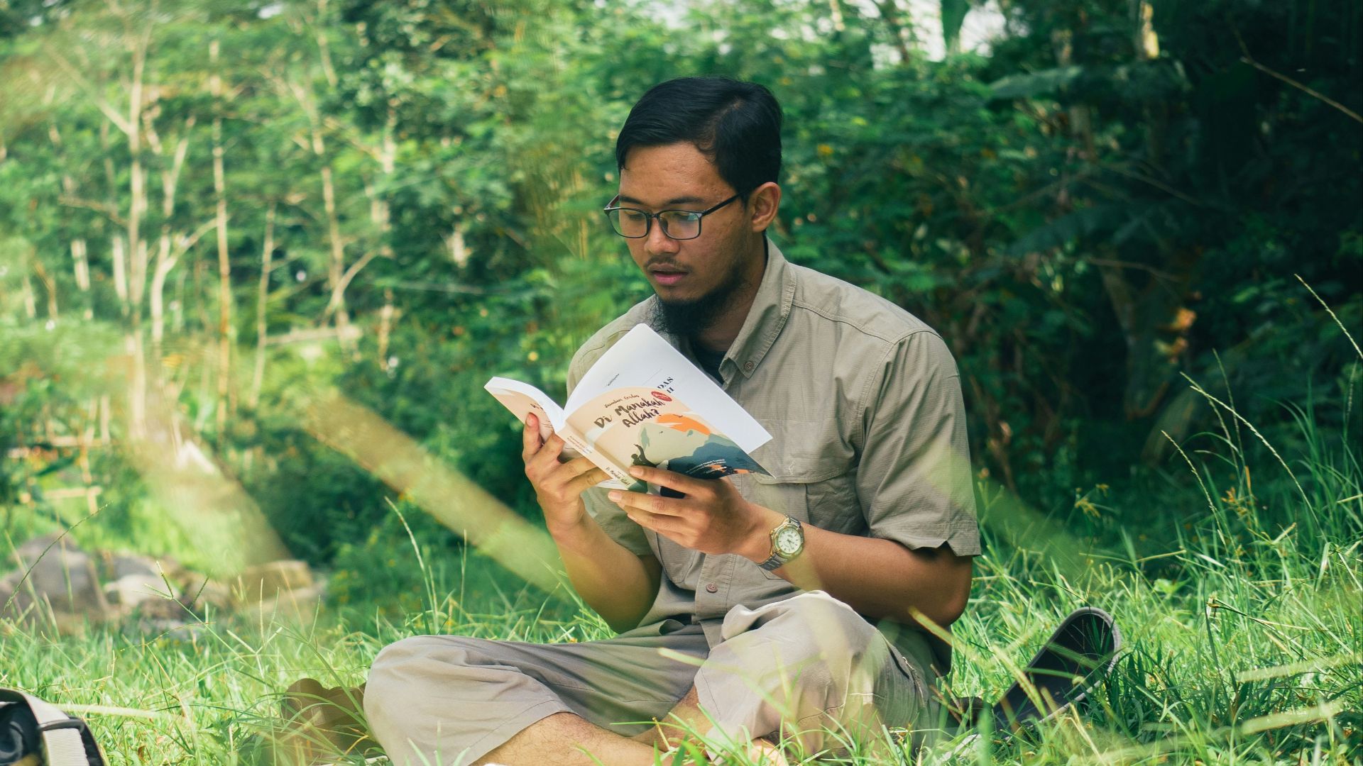 a man sitting in the grass reading a book
