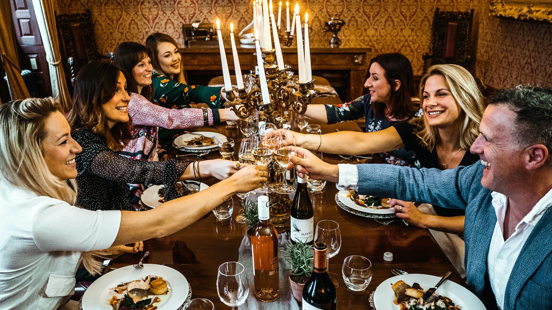 group of people sitting on chair in front of table with plates and drinking glasses