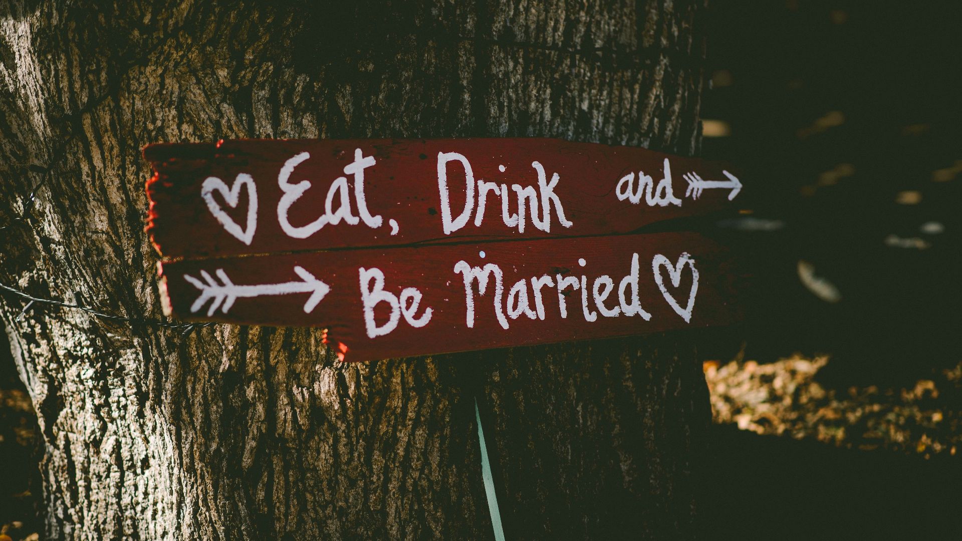 red and white eat, drink, and be married signage near brown tree