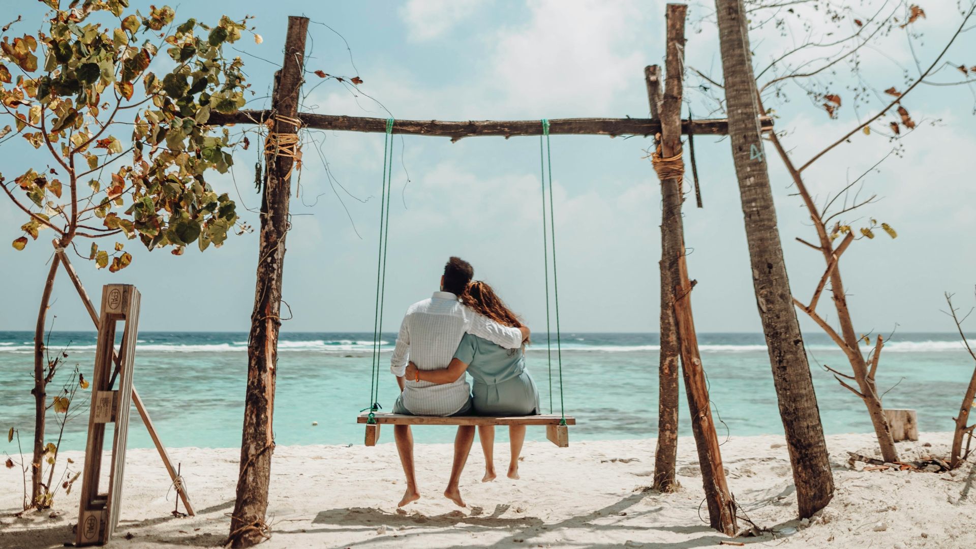 a couple sitting on a bench on a beach