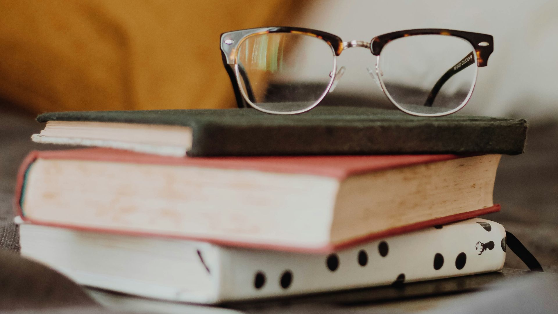 club master eyeglasses on pile of three books