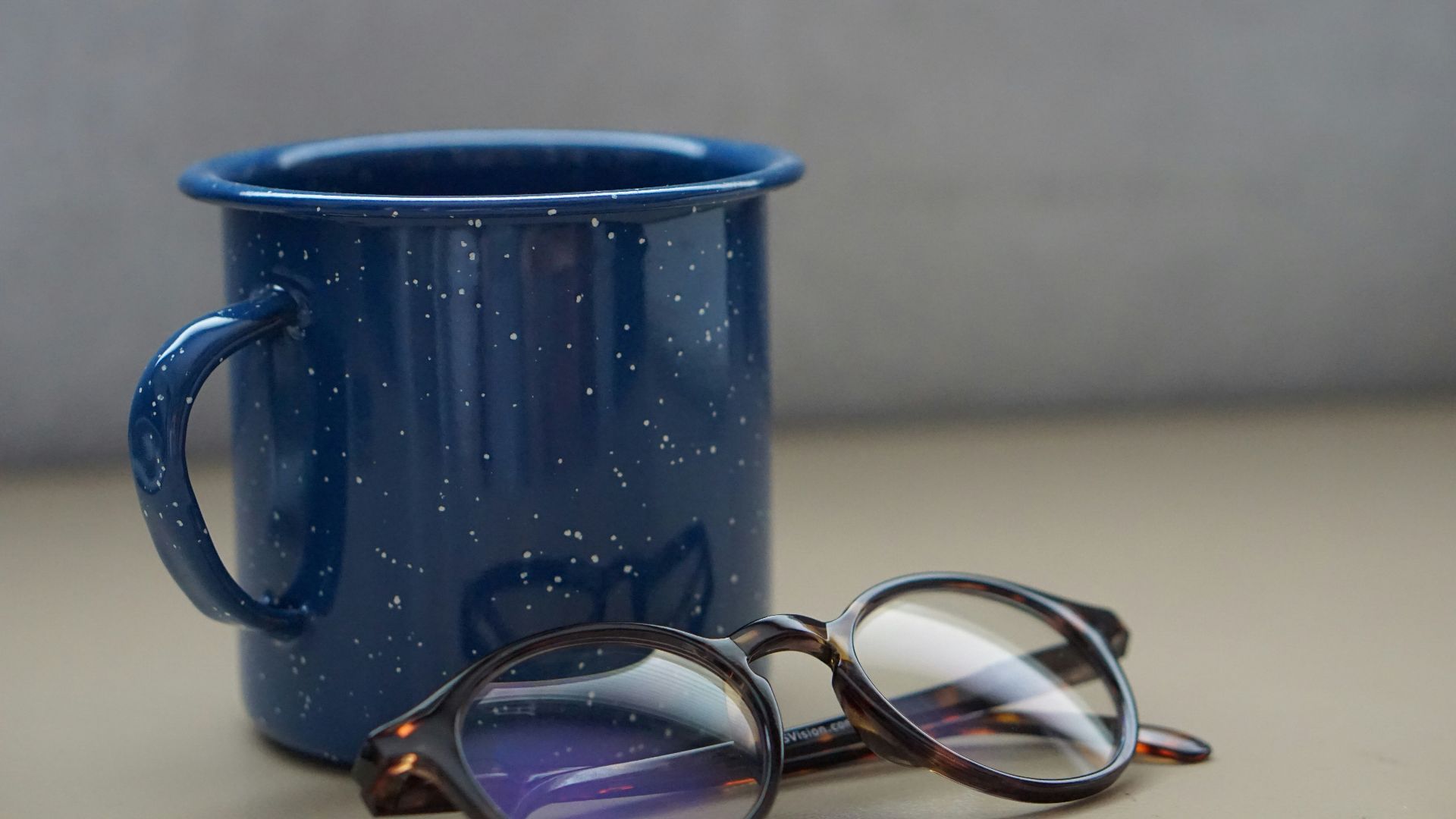 black metal mug beside eyeglasses