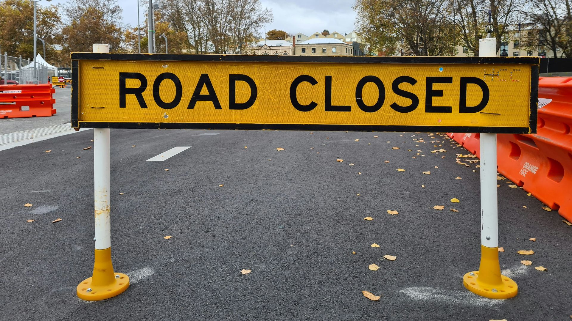 a yellow road closed sign sitting on the side of a road