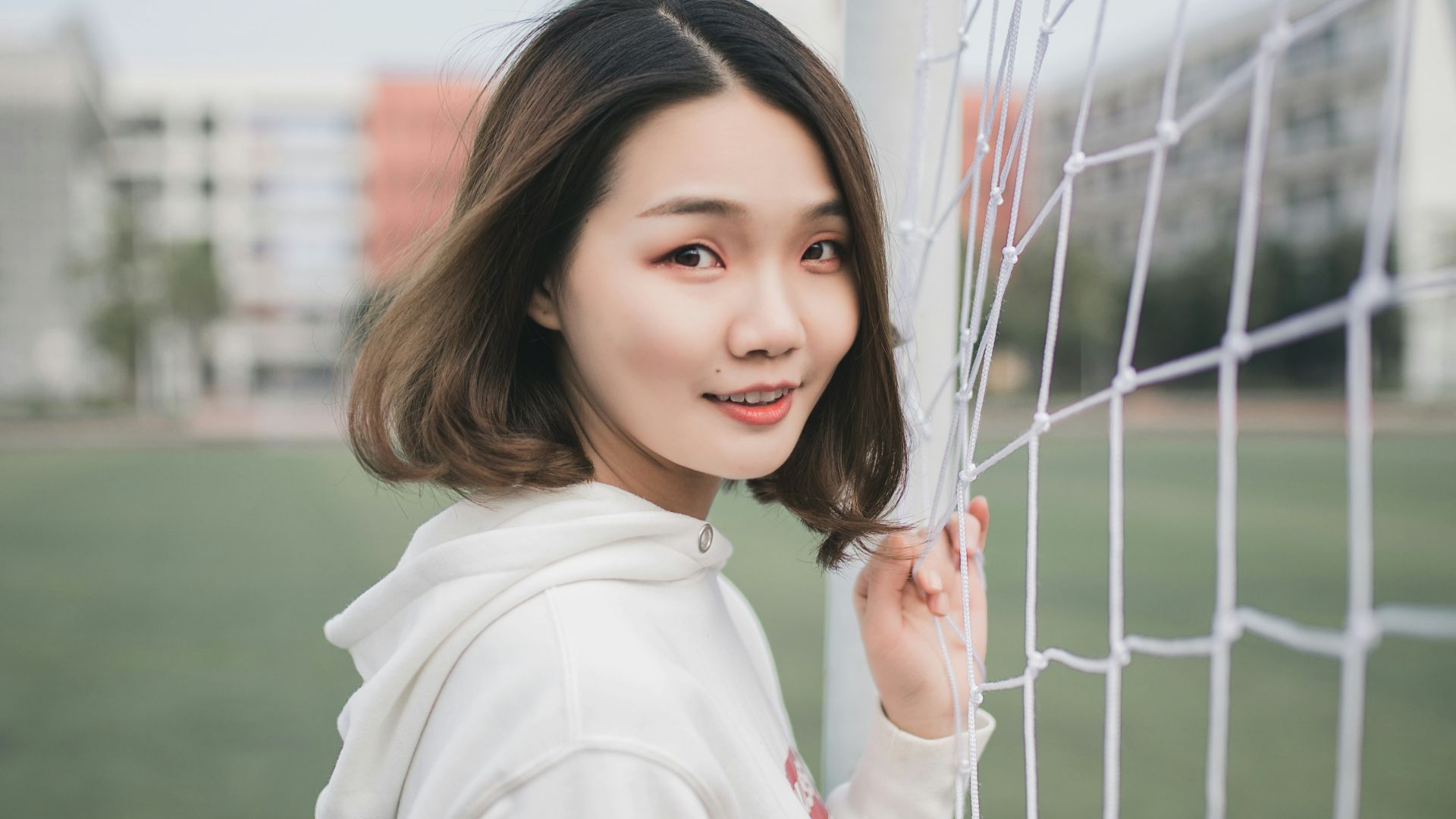 man in white pullover hoodie standing beside white goal net
