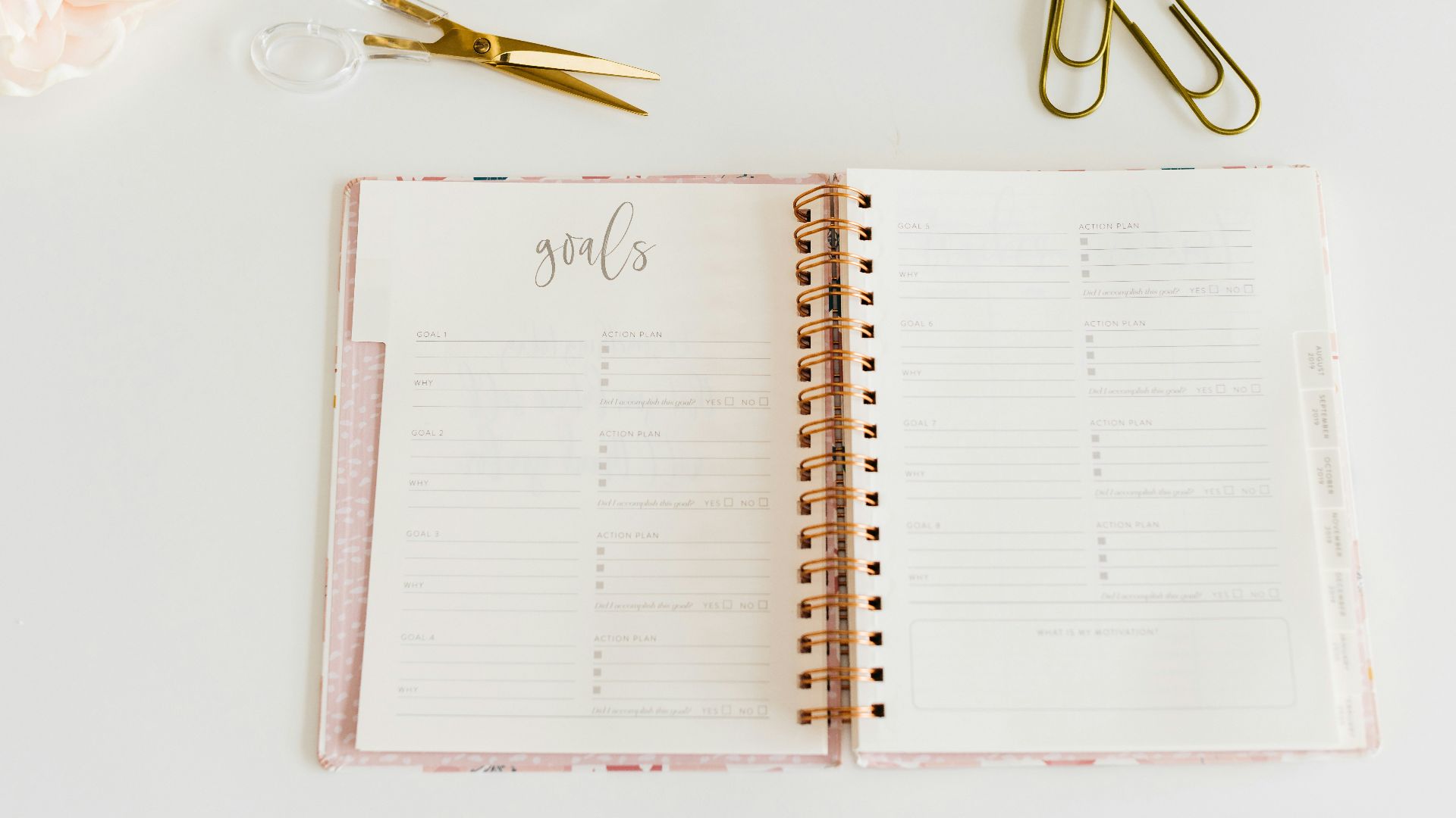 scissors and two paper clips beside opened spiral notebook