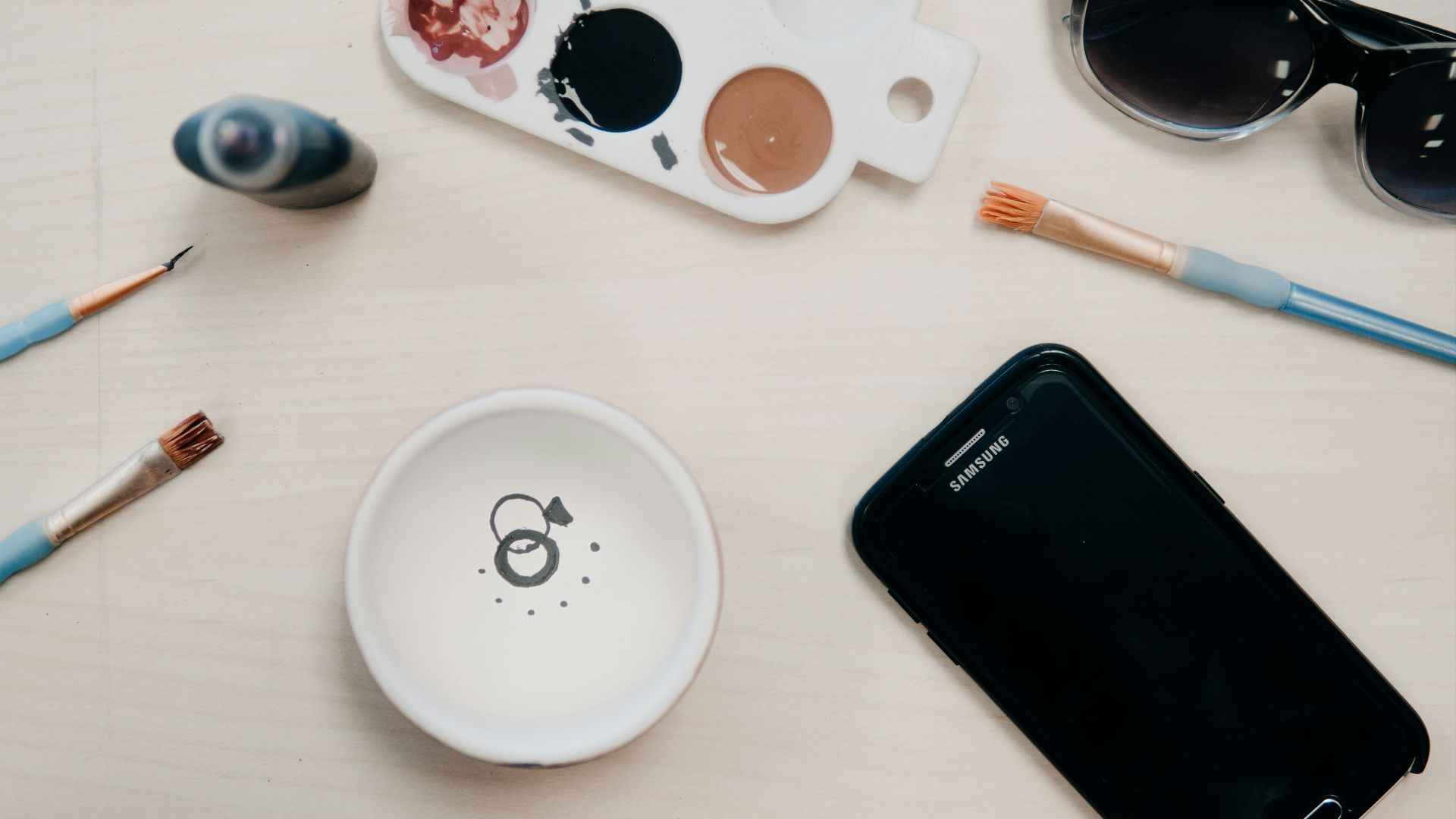 flat lay photo of black Samsung Galaxy Android smartphone near three blue paint brushes