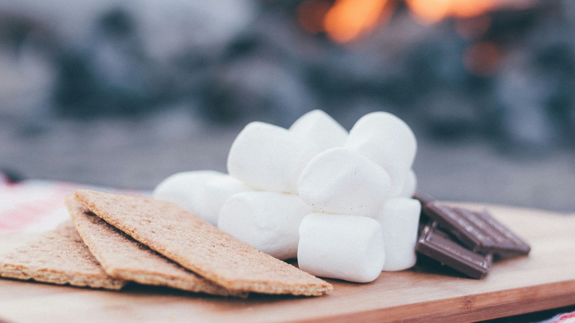 biscuits, marshamallows and chocolate bars on wooden tray