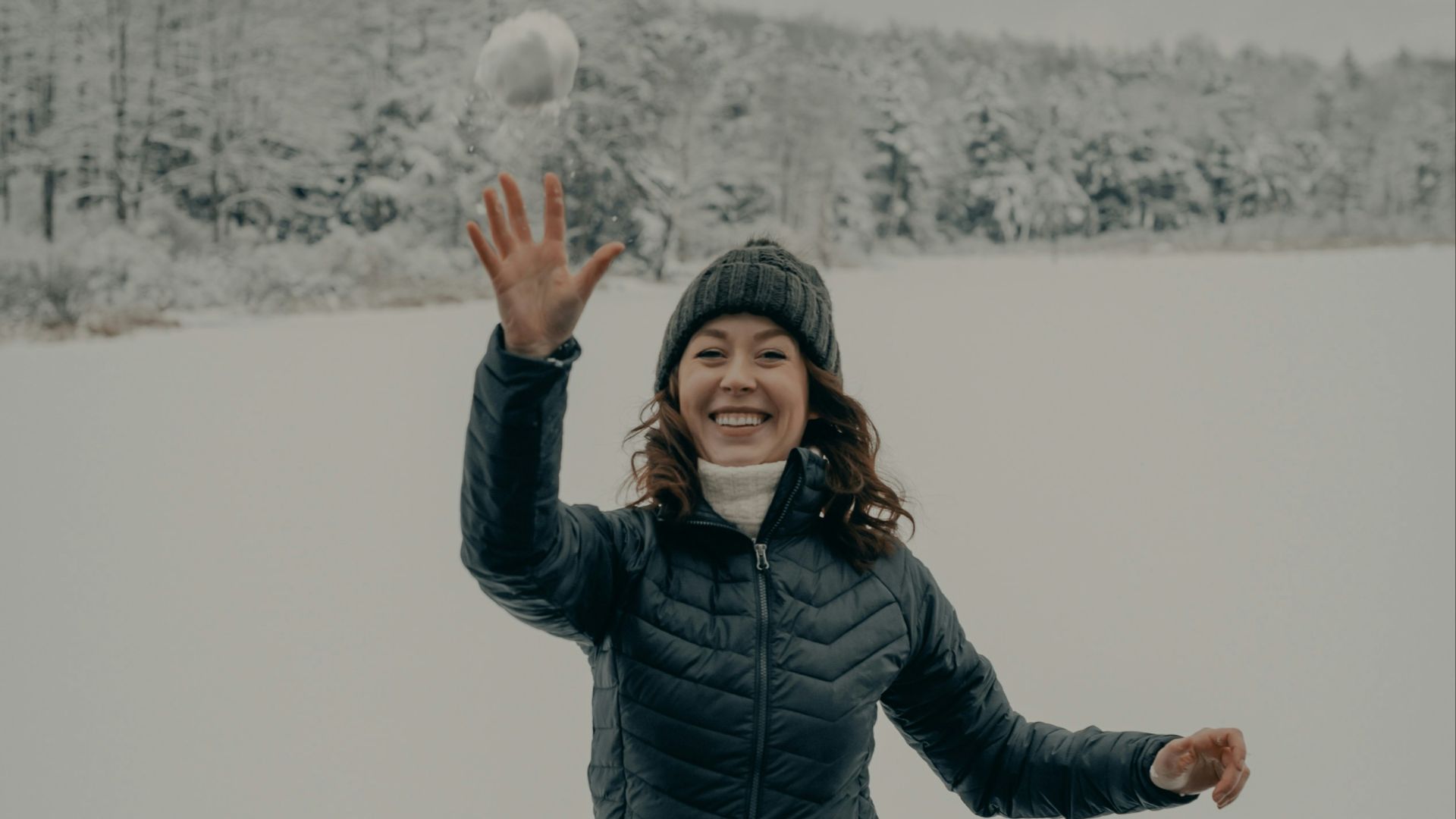 woman in black jacket and blue denim jeans standing on snow covered ground during daytime
