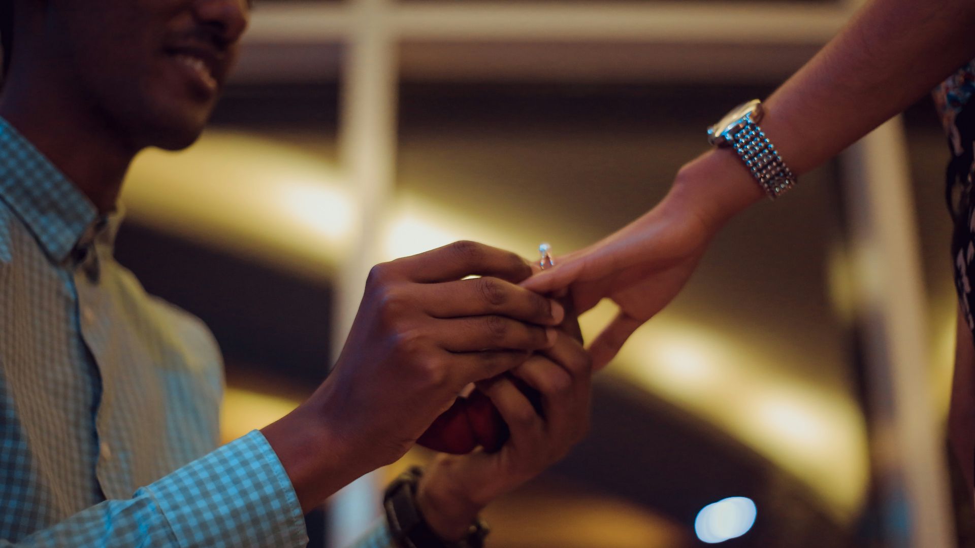 man putting ring on woman's hand