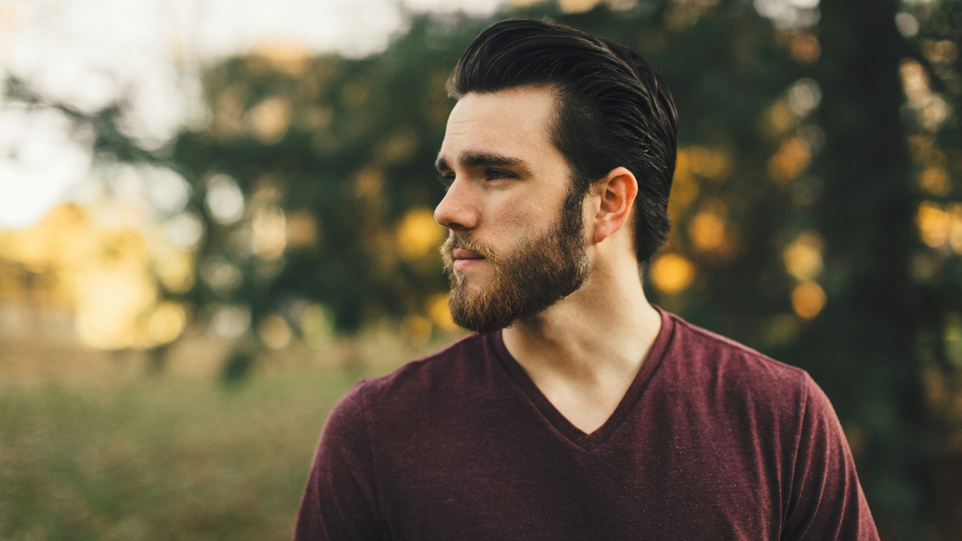 man wearing maroon V-neck t-shirt in forest