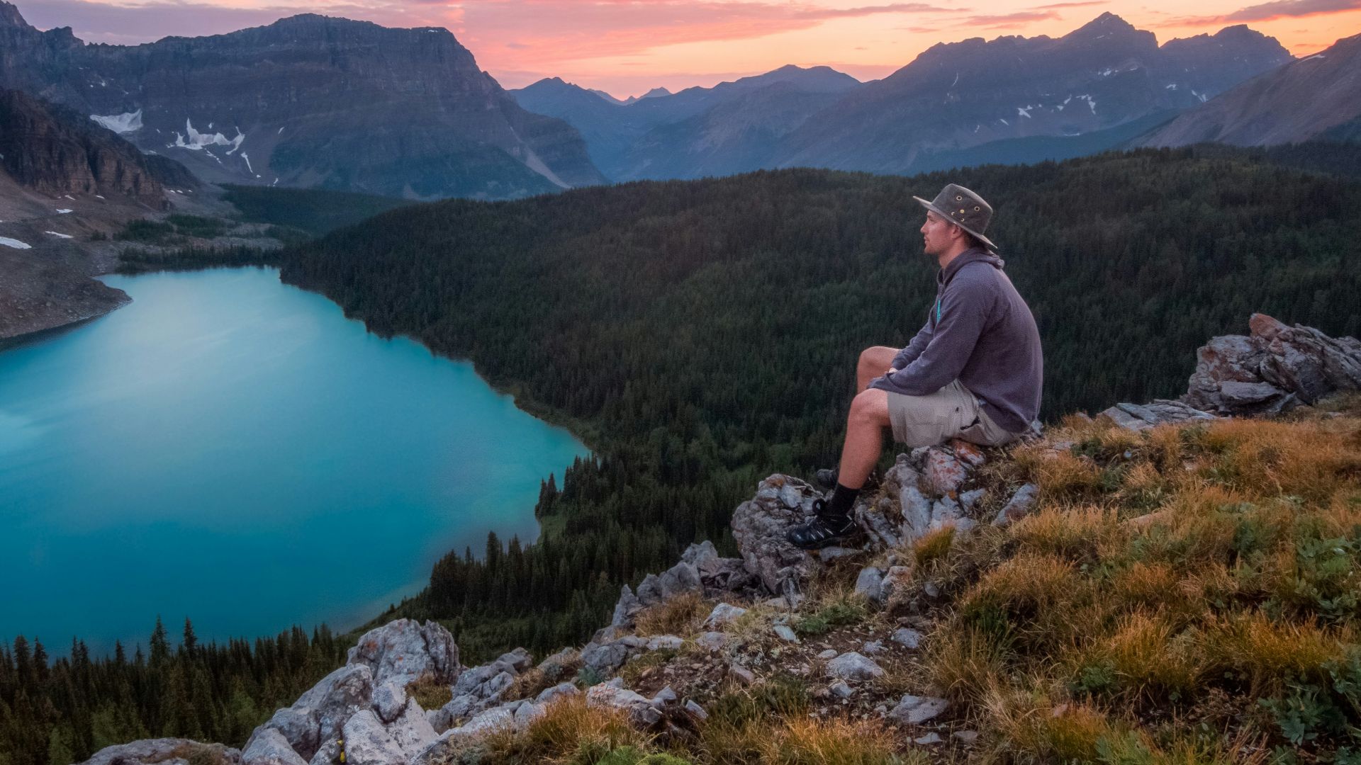 man looking on mountain sitting on rock