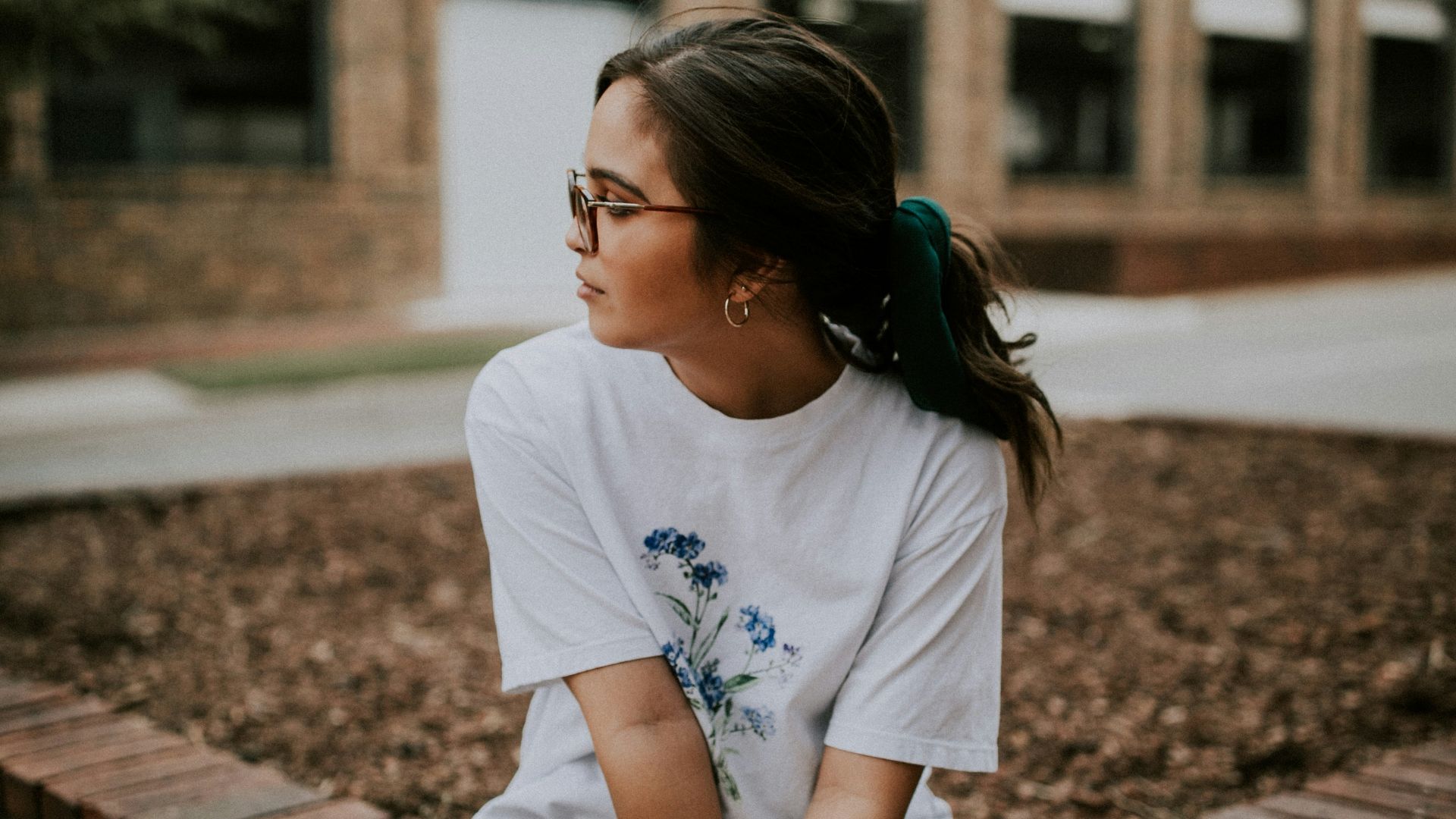 shallow focus photo of woman in white crew-neck T-shirt sitting on concrete bench