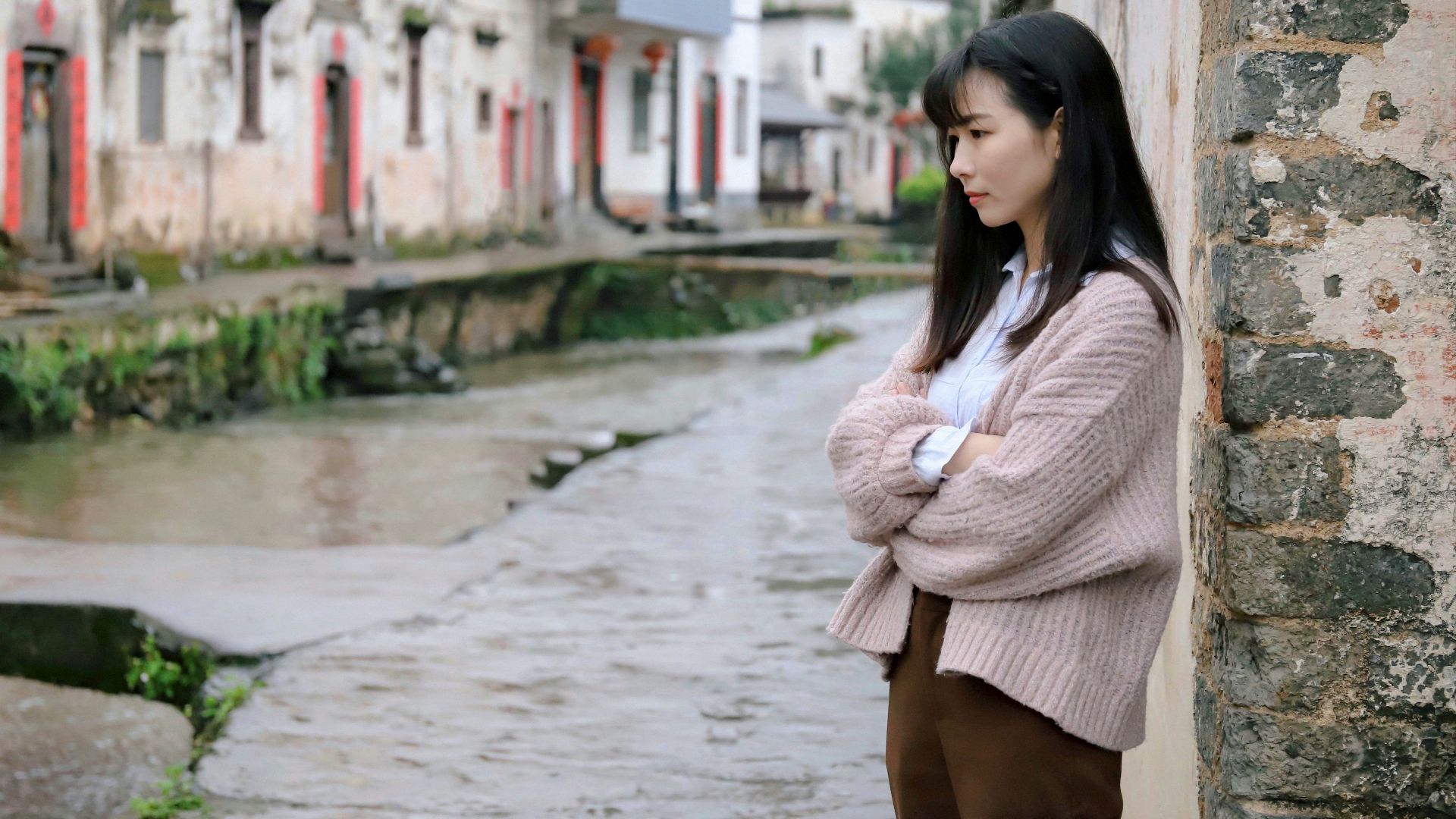 woman leaning on beige concrete wall